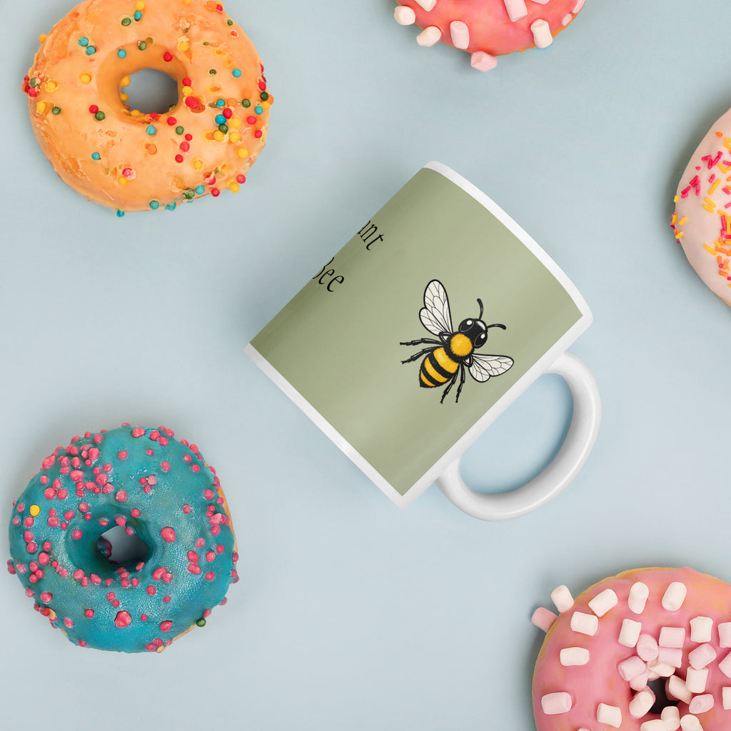 Sage green ceramic coffee mug at an angle, showing bee illustration