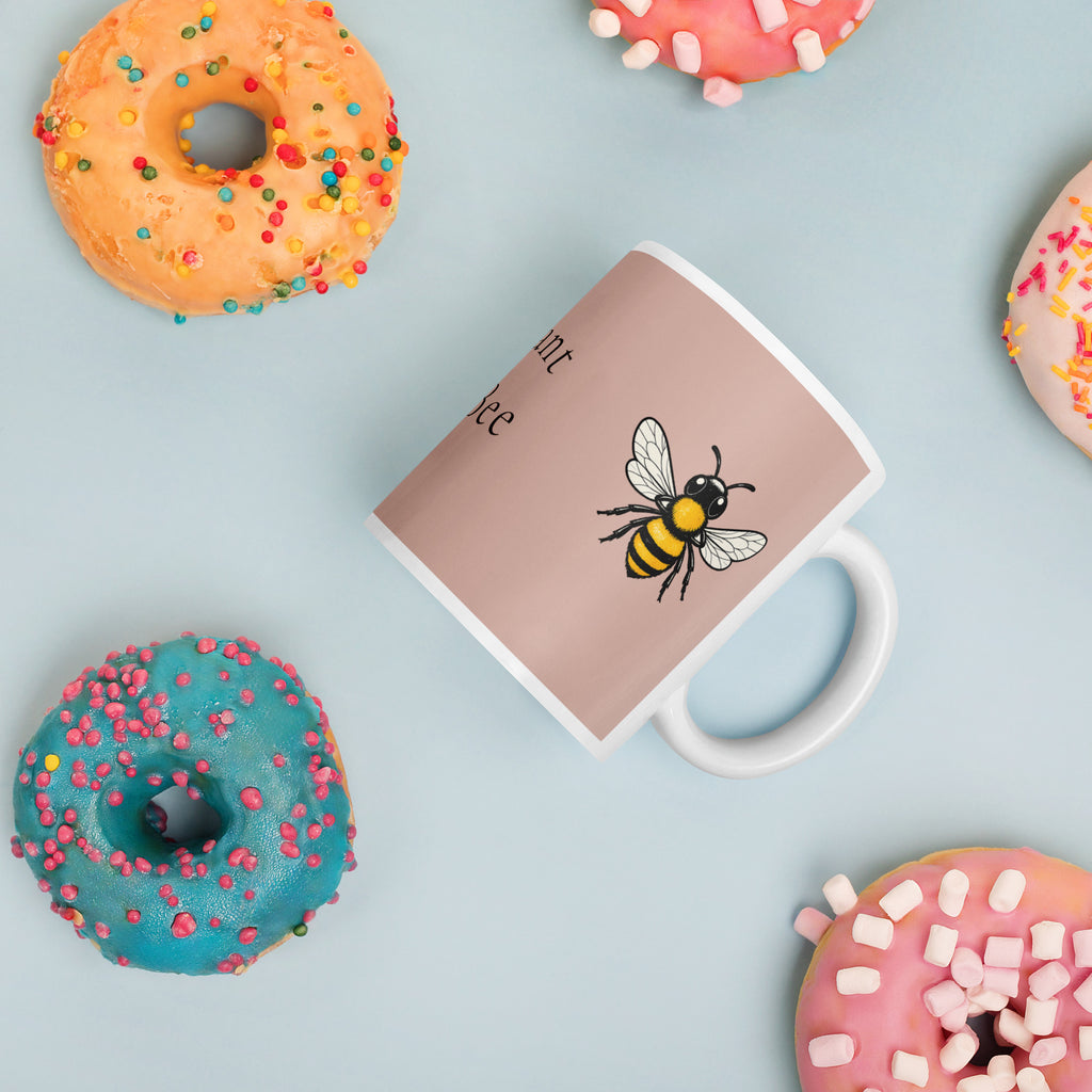 Dusty rose ceramic coffee mug with white rim and handle; black and yellow bee illustration.