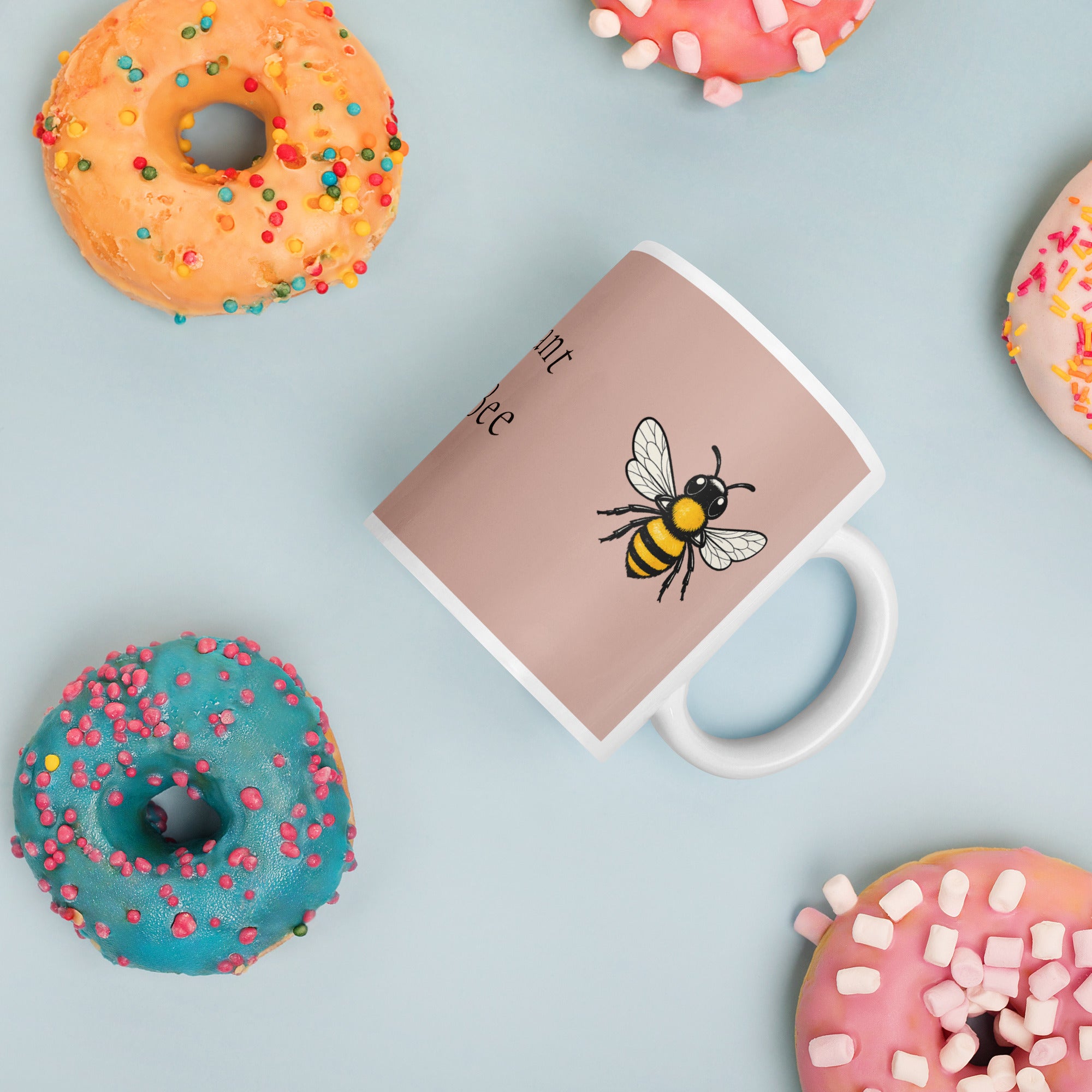 Dusty rose ceramic coffee mug with white rim and handle; black and yellow bee illustration.