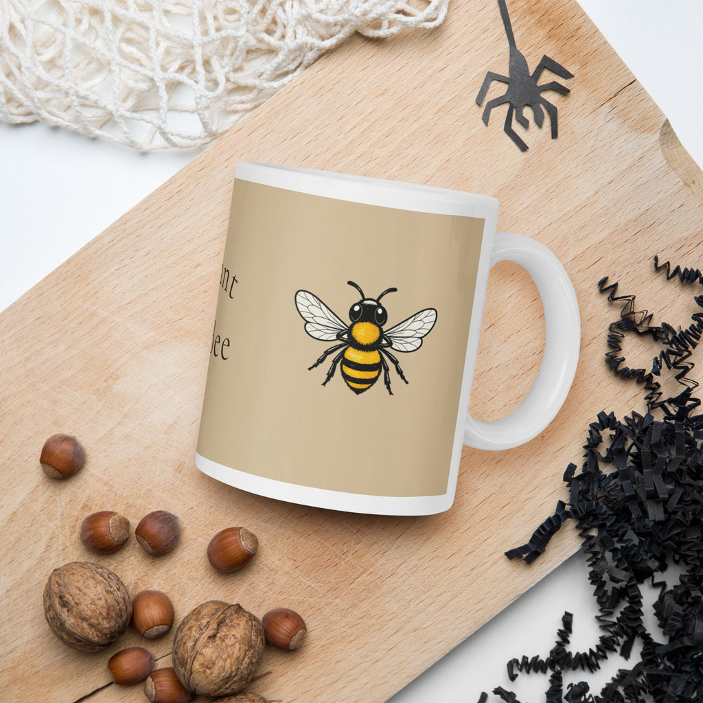 Beige ceramic coffee mug on wooden board, bee illustration on front with partial text