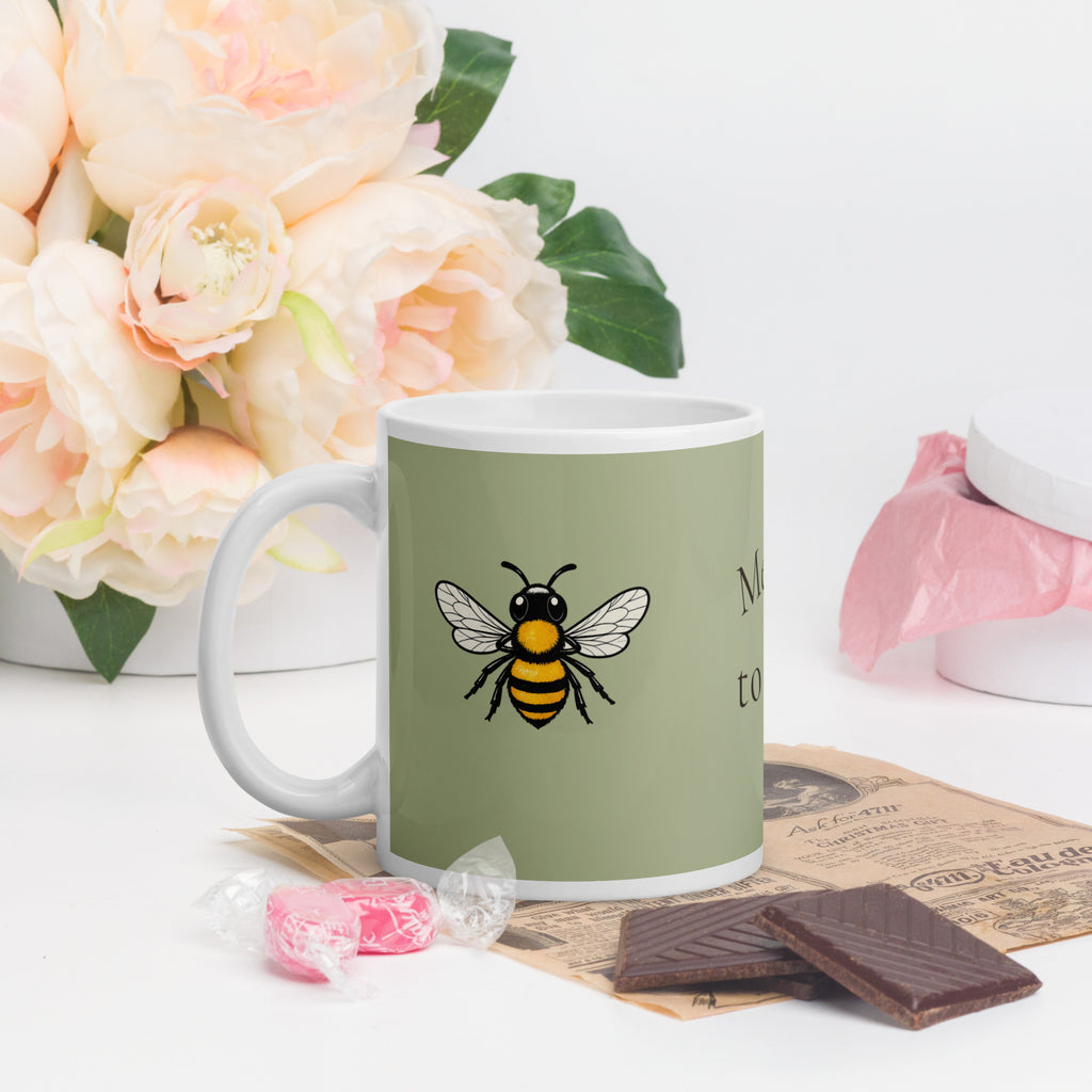 Sage green ceramic coffee mug with white handle and bee illustration, front view