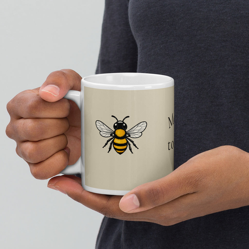 Light beige ceramic mug with centered bee illustration, white rim and handle