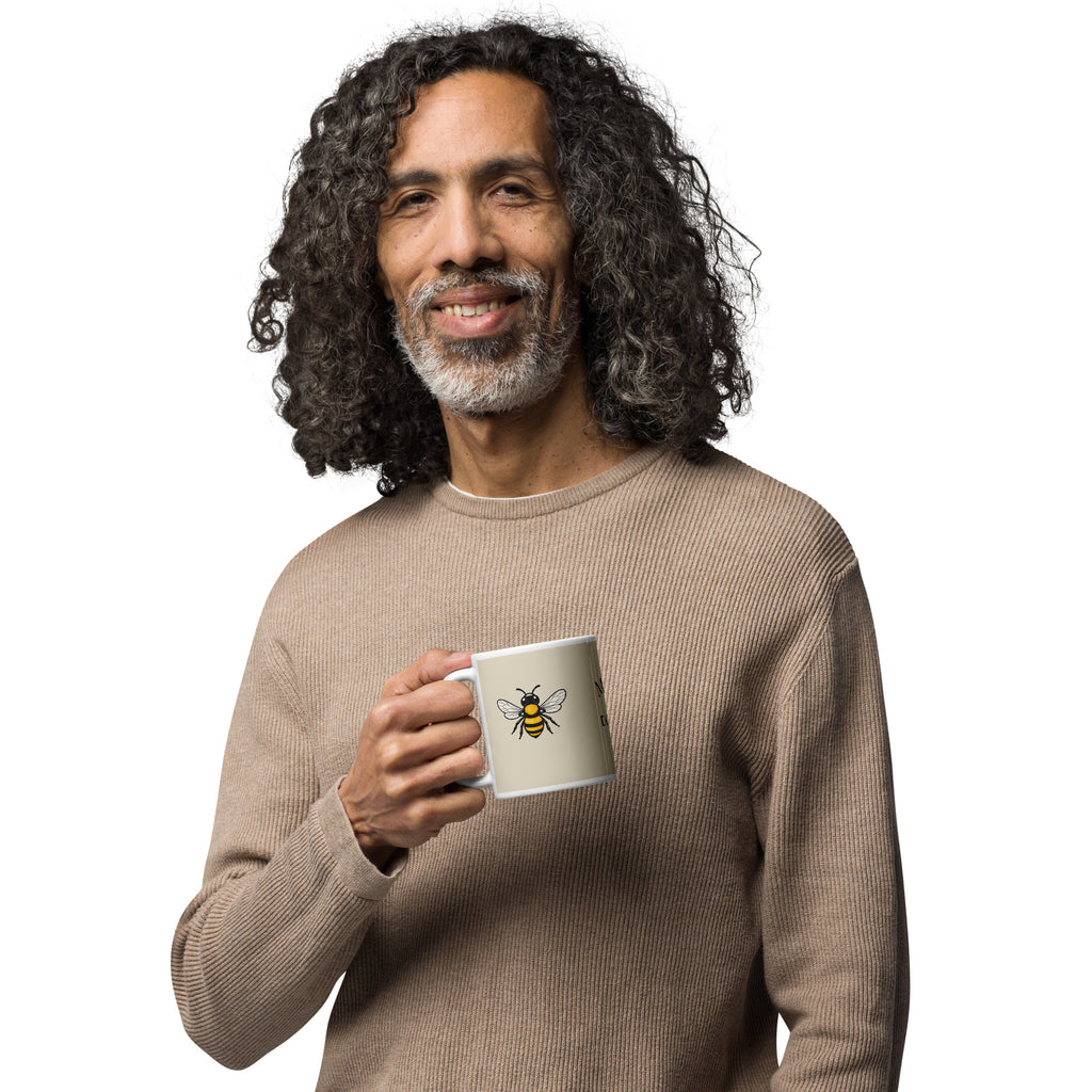Light beige ceramic coffee mug with bee illustration, held in one hand