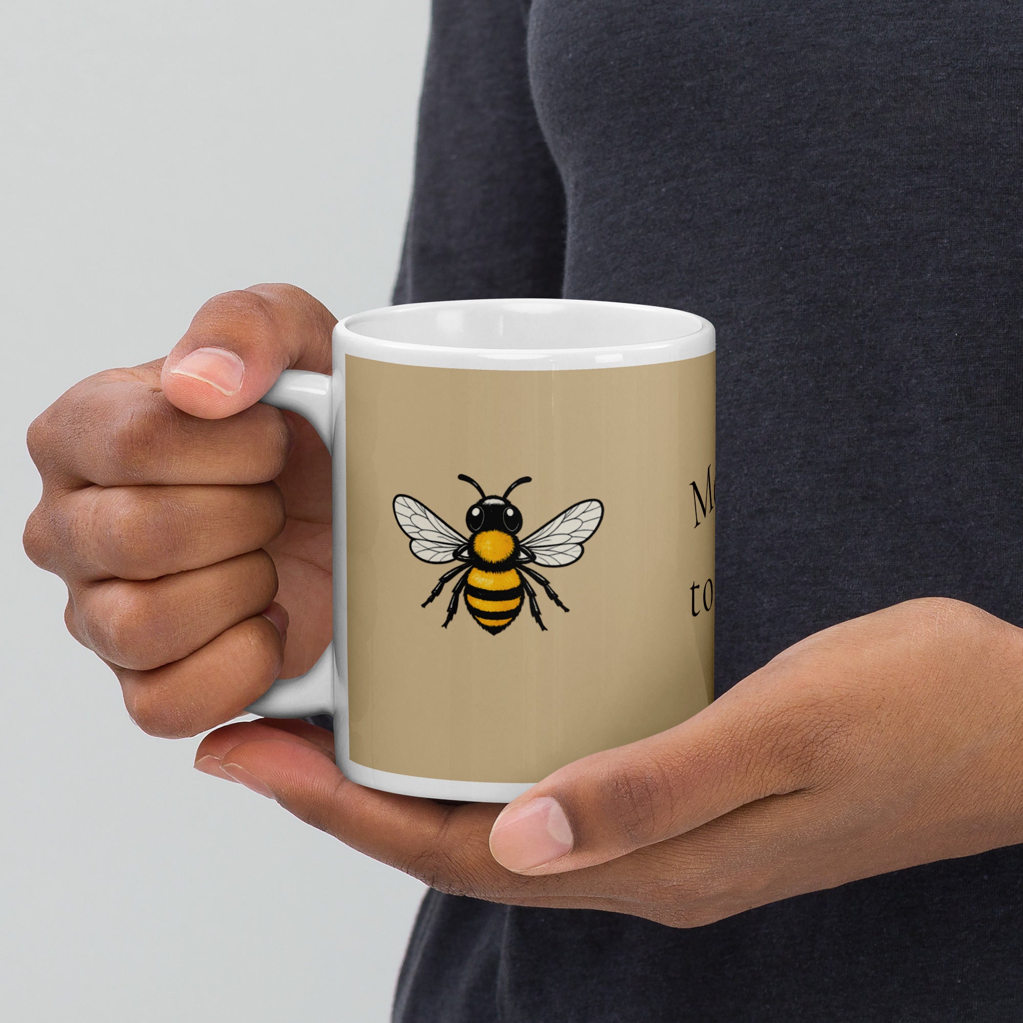 Beige ceramic coffee mug with white rim and handle, black-and-yellow bee illustration
