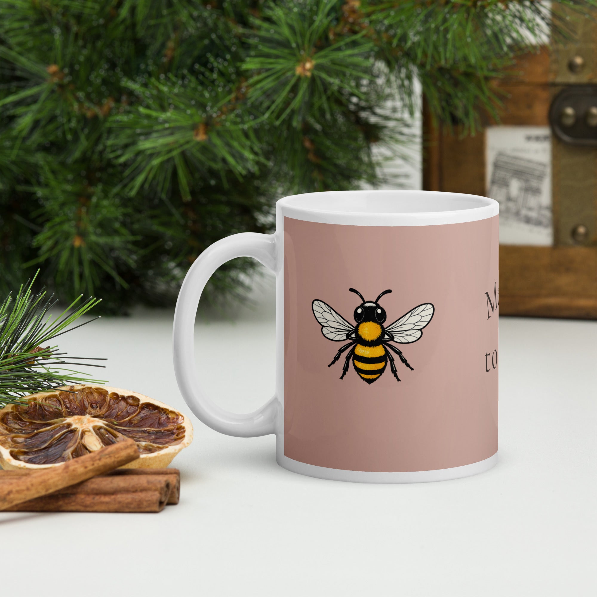Dusty rose ceramic mug with white handle and rim, featuring a bee illustration