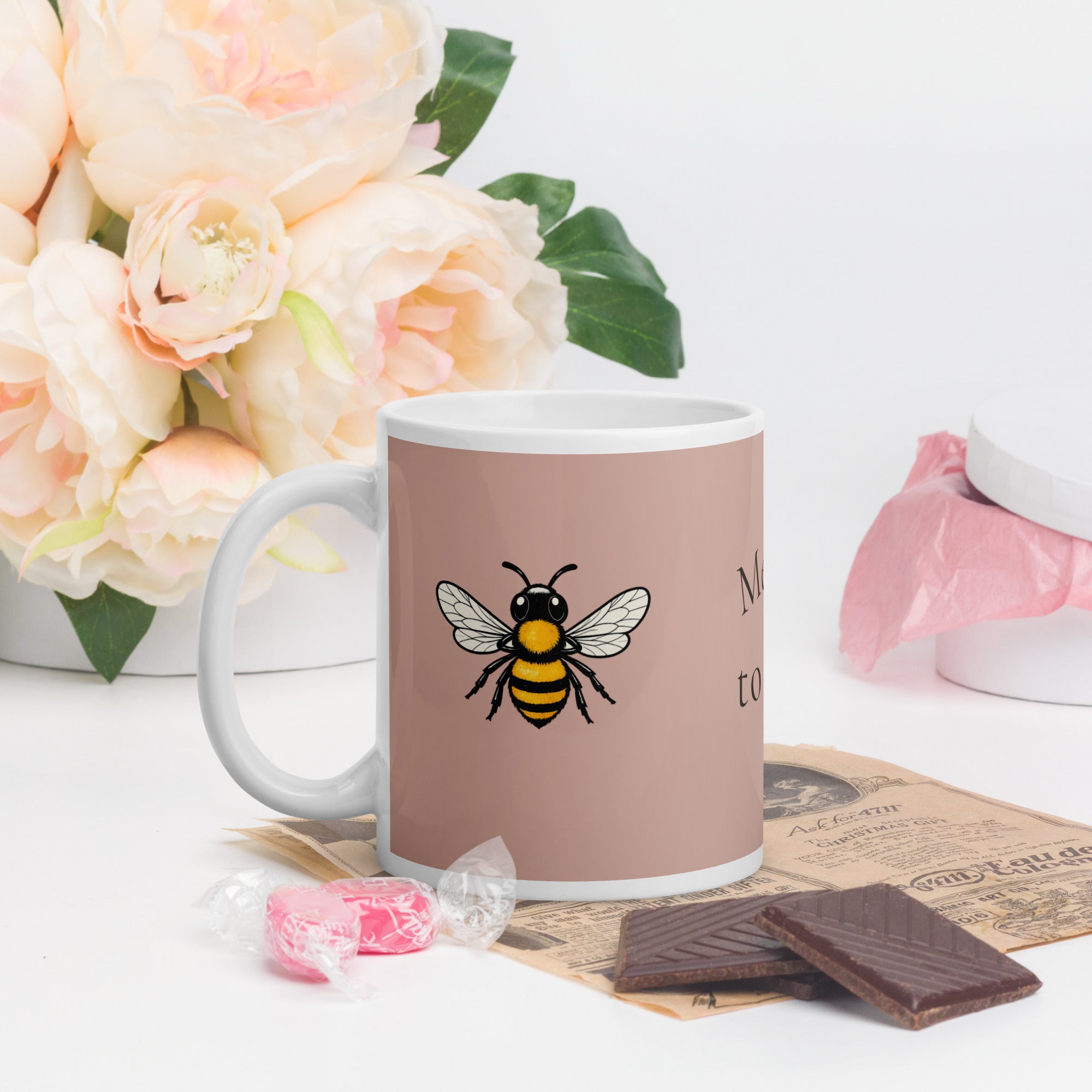 Dusty rose ceramic coffee mug with bee illustration and white handle.