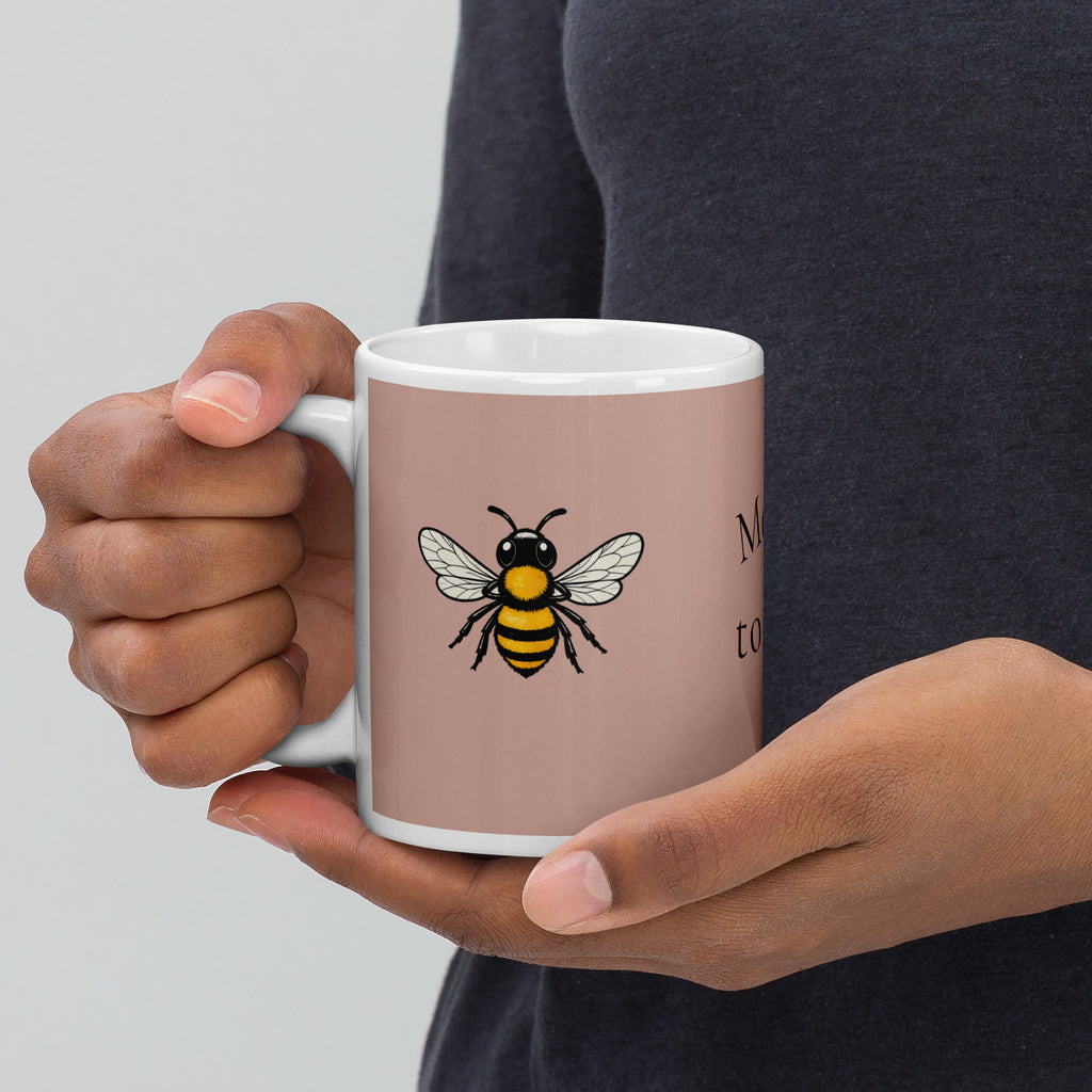 Dusty rose ceramic mug with bee illustration held by hands, white rim