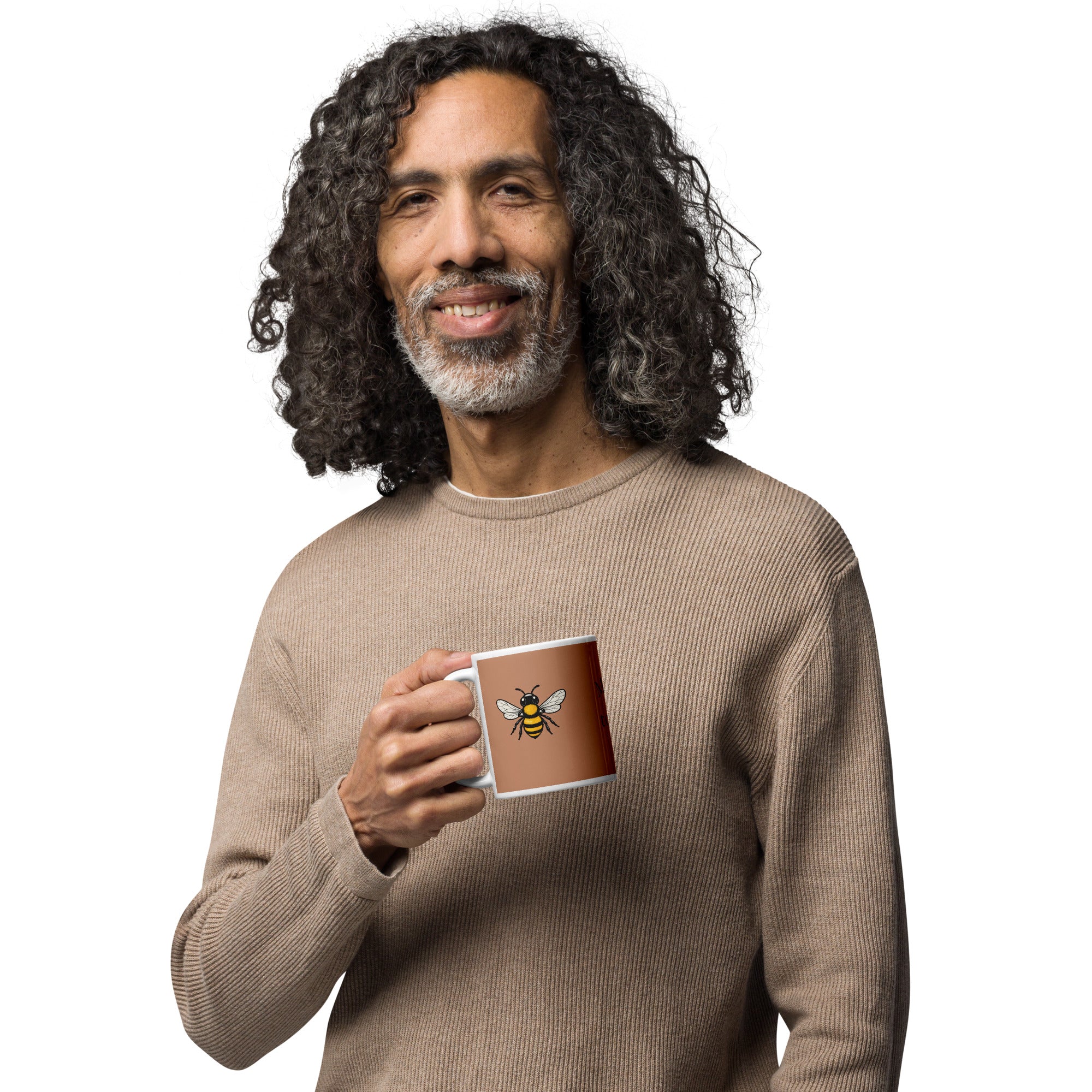 Brown ceramic mug with bee illustration, held by a smiling person in a sweater