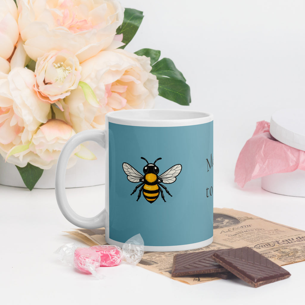 Blue ceramic coffee mug with centered bee illustration, white handle and rim.