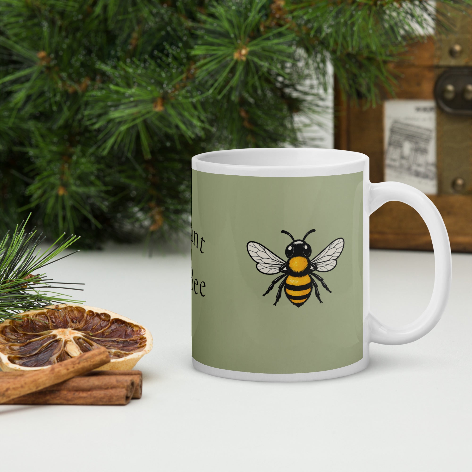 Sage green ceramic coffee mug with white handle, bee illustration on front