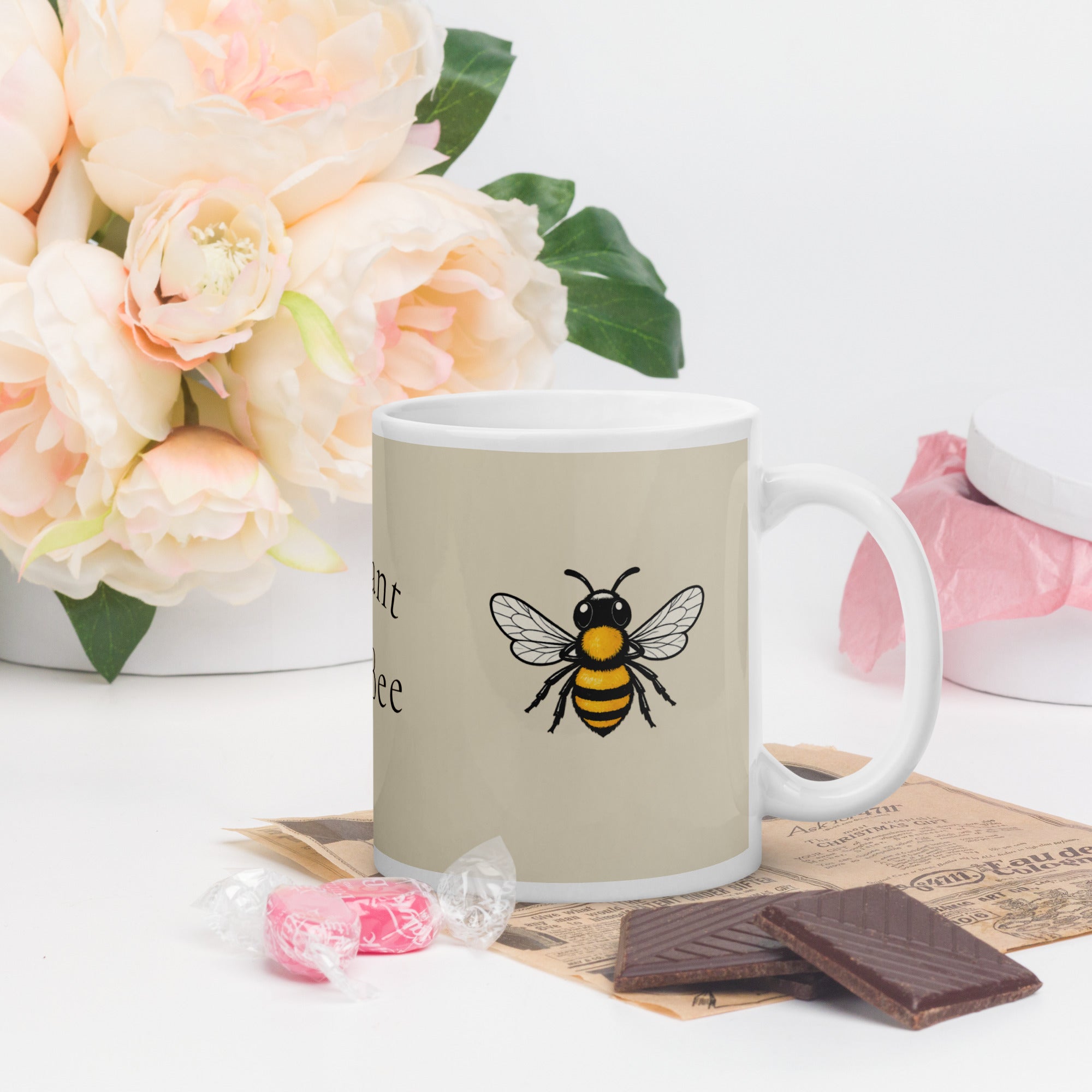 Light beige ceramic mug with bee illustration and partial text on left