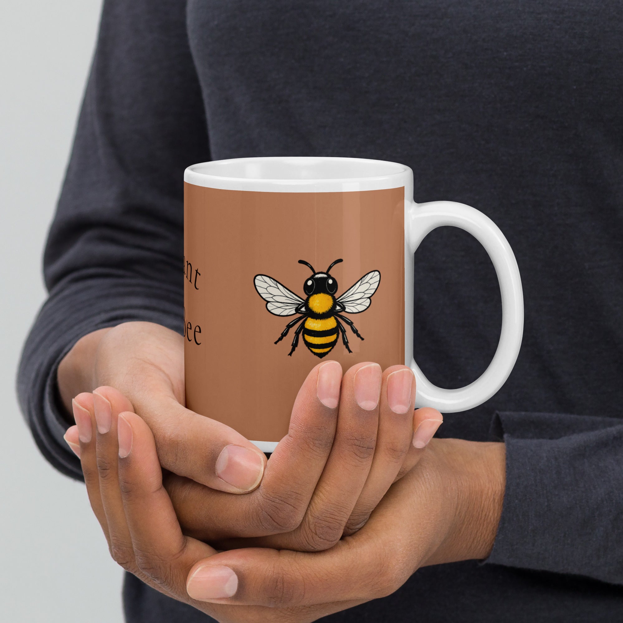 Brown ceramic mug with white handle and bee illustration, held with two hands