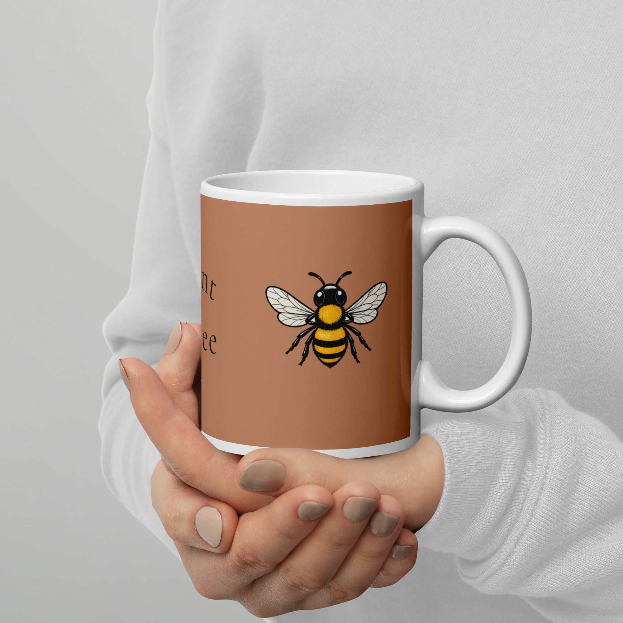 Brown ceramic mug with bee illustration, held in hands over a white sleeve.