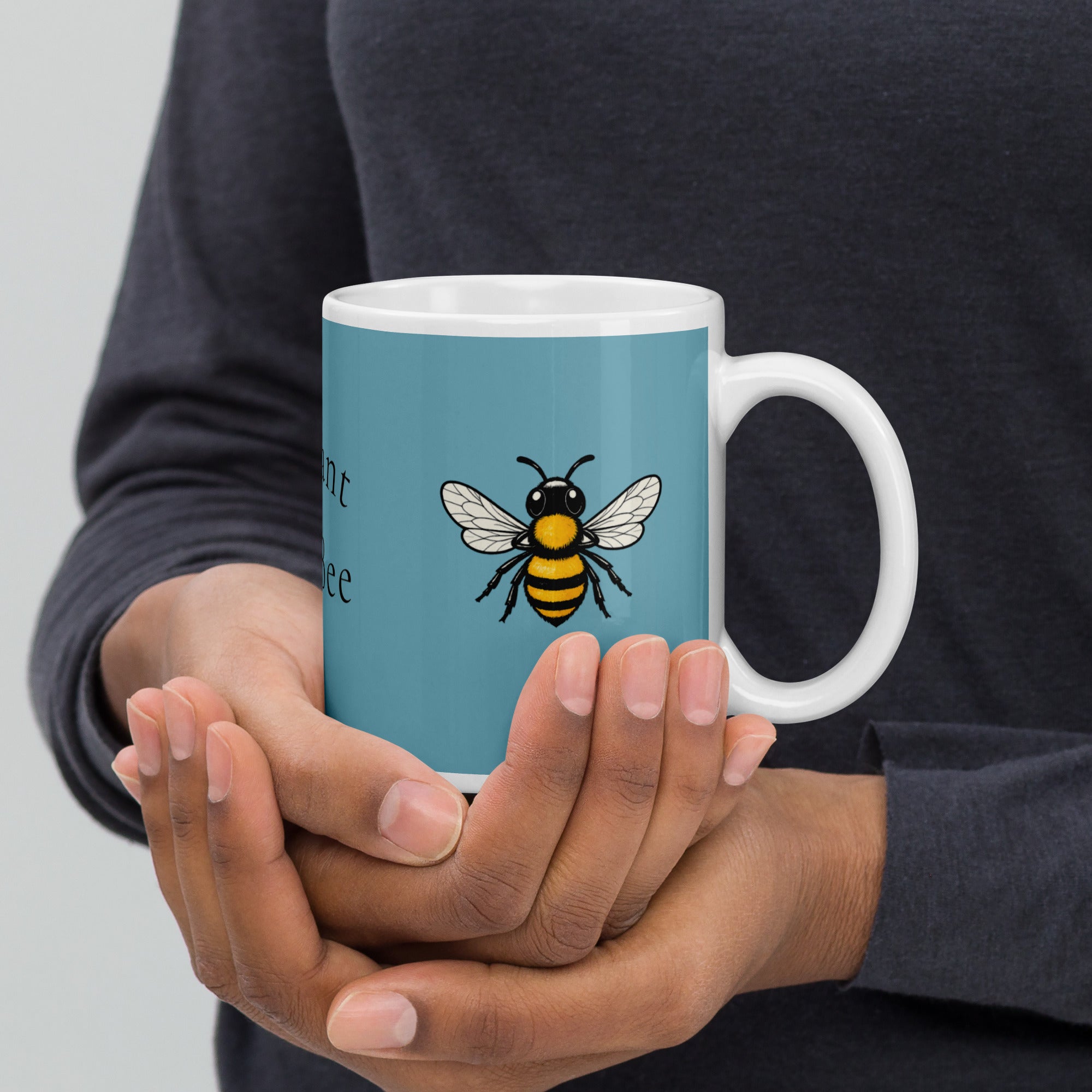 Hands holding a blue ceramic coffee mug with bee illustration