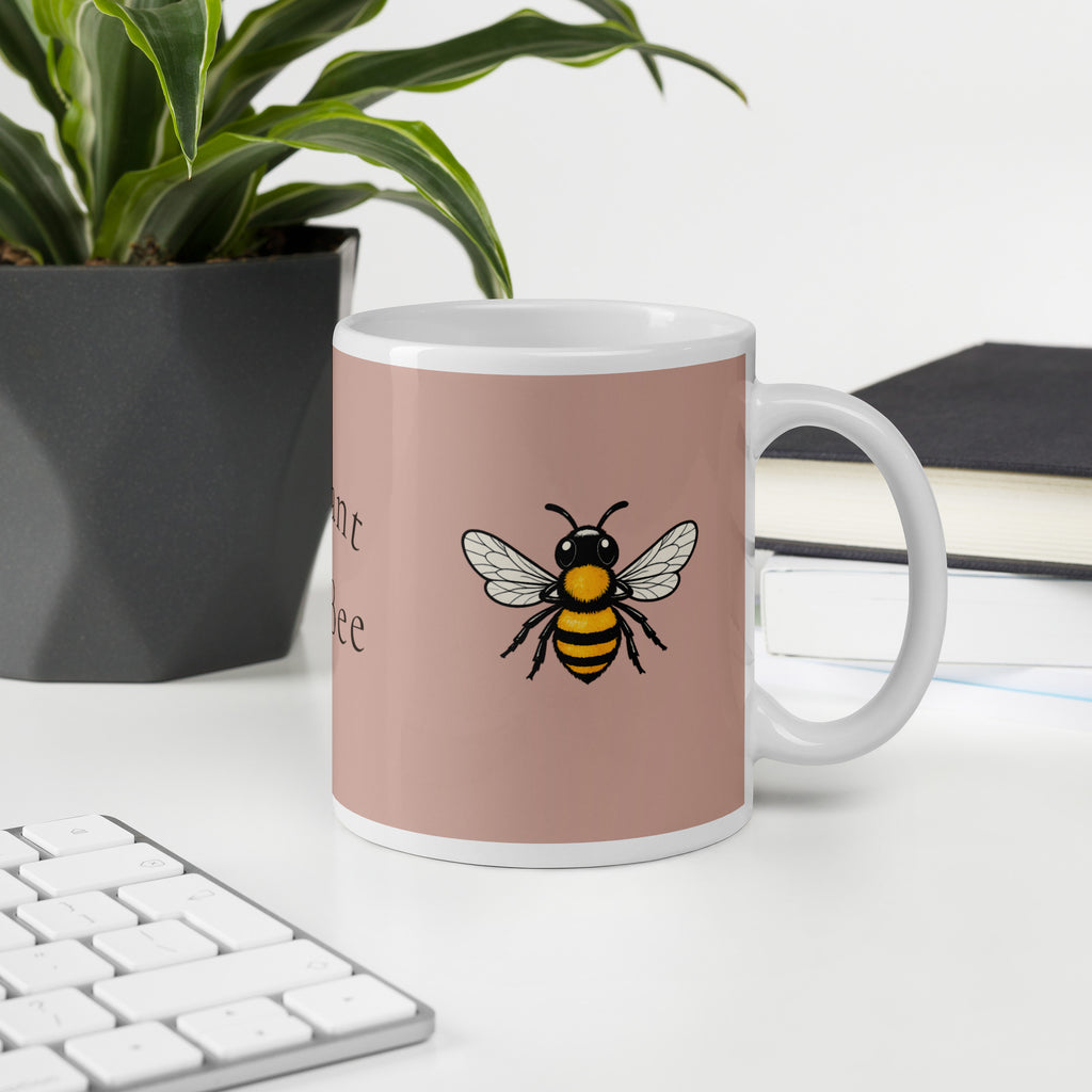 Dusty rose ceramic mug with white rim and handle, bee illustration and partial text.