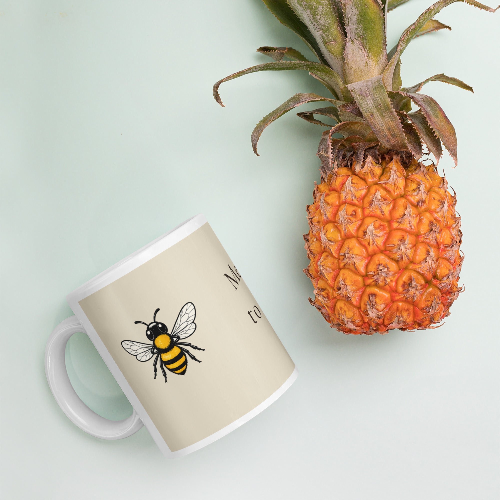 Light beige ceramic mug with bee illustration, tilted on a surface