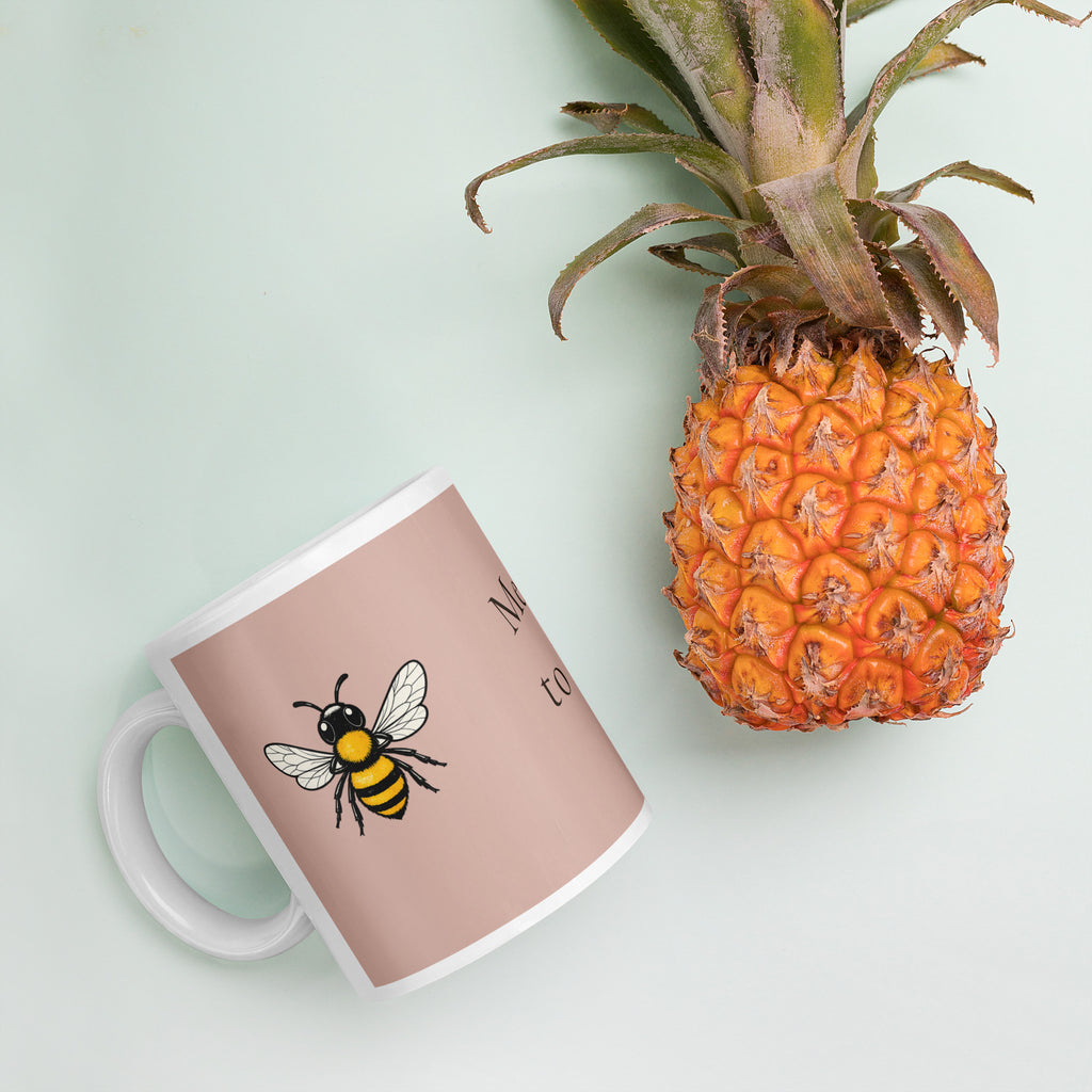 Dusty rose ceramic mug with white handle and bee illustration on the front.
