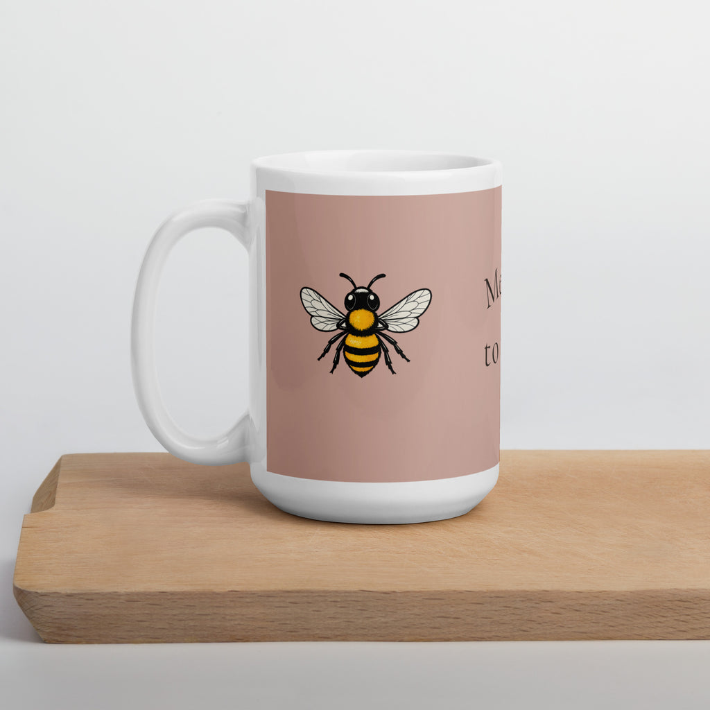 Dusty rose ceramic mug with white handle, base, and center bee illustration