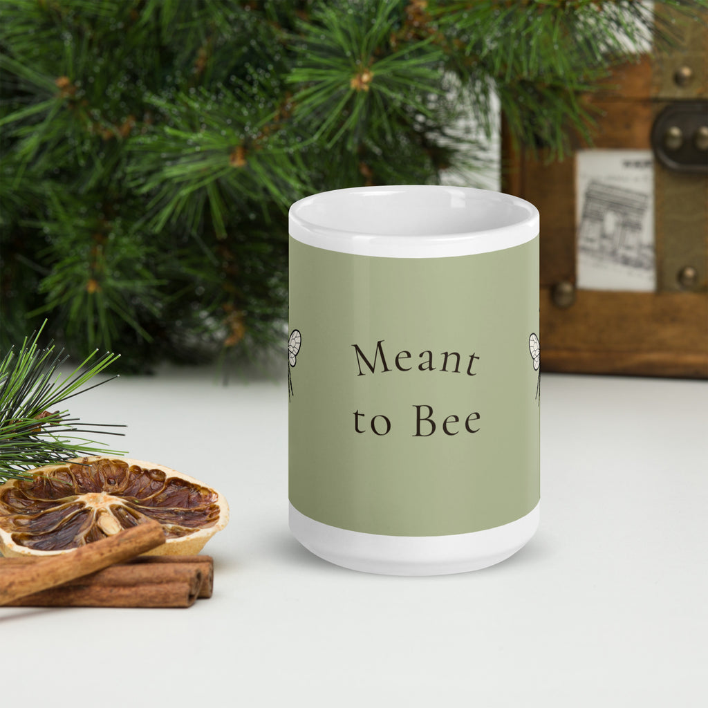 Sage green ceramic mug with 'Meant to Bee' text on front and white rim