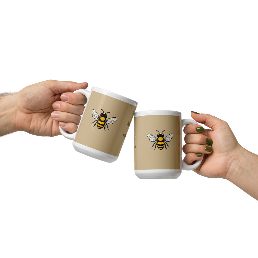 Two beige ceramic mugs with white rims held by two people, bee illustrations facing outward