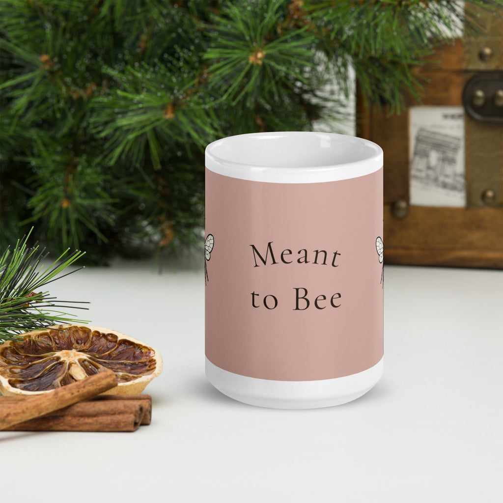 Dusty rose ceramic coffee mug with “Meant to Bee” text on front.