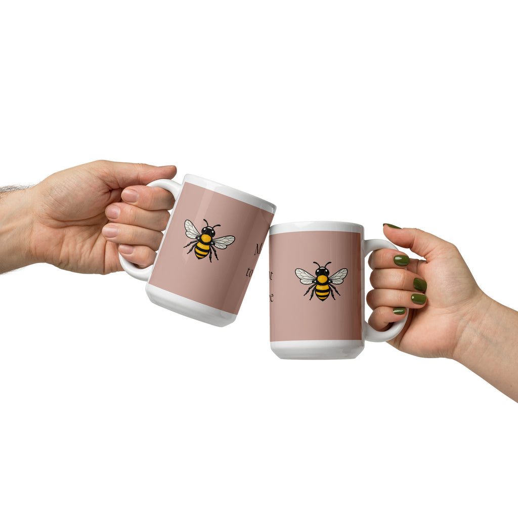 Dusty rose ceramic mugs with white rims and handles, bee illustrations on both.