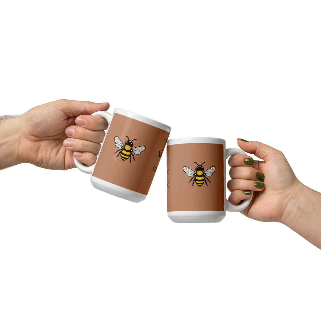 Two white and brown ceramic mugs with bee illustrations, clutched in hands facing each other.