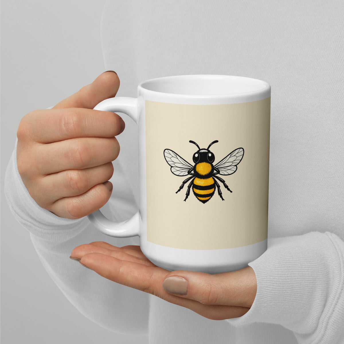 Cream ceramic mug with large bee illustration on front, showing white handle