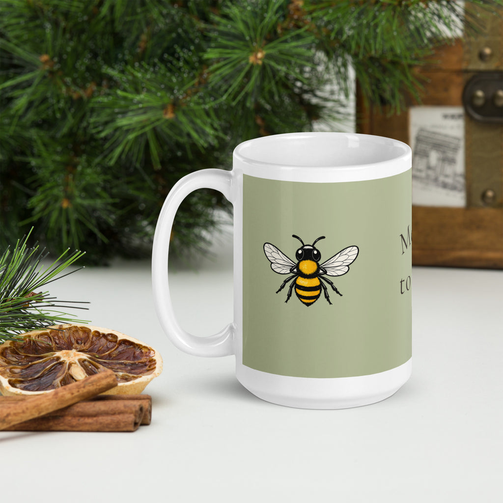 Sage green ceramic coffee mug with white handle, bee illustration on front panel
