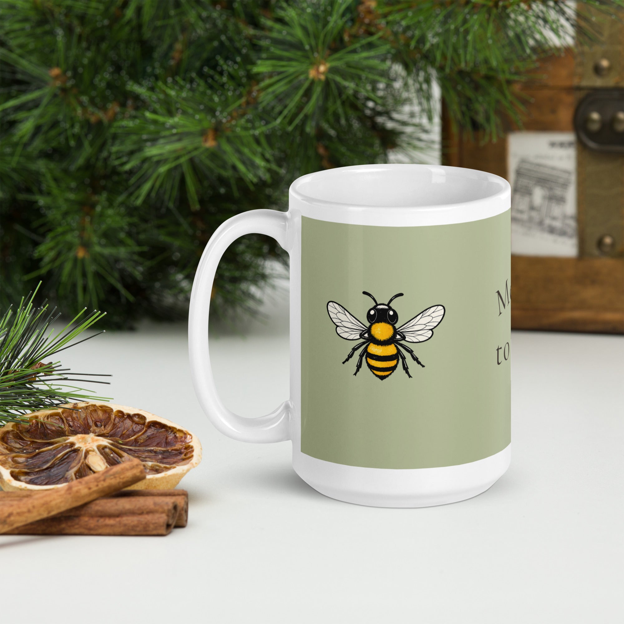 Sage green ceramic coffee mug with white handle, bee illustration on front panel