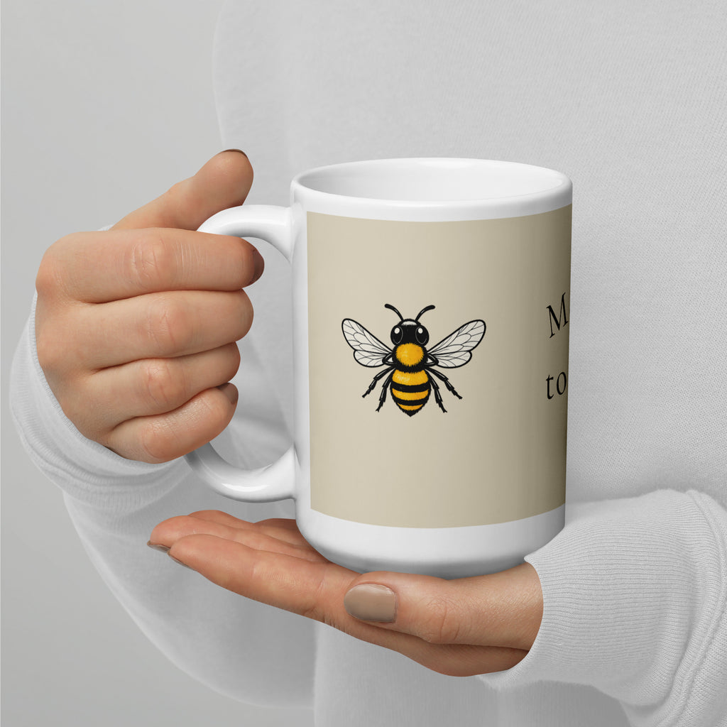 Light beige ceramic coffee mug with white handle and bee illustration on front
