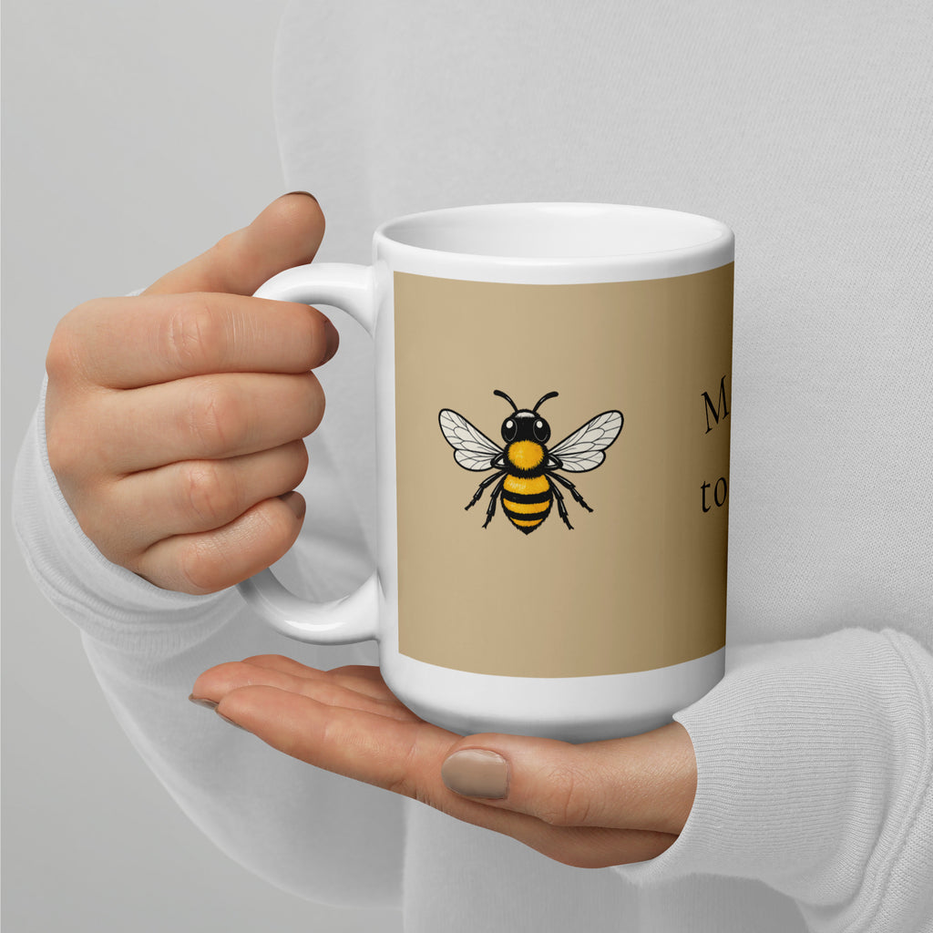 Beige ceramic mug with white handle and rim, yellow-and-black bee graphic on front