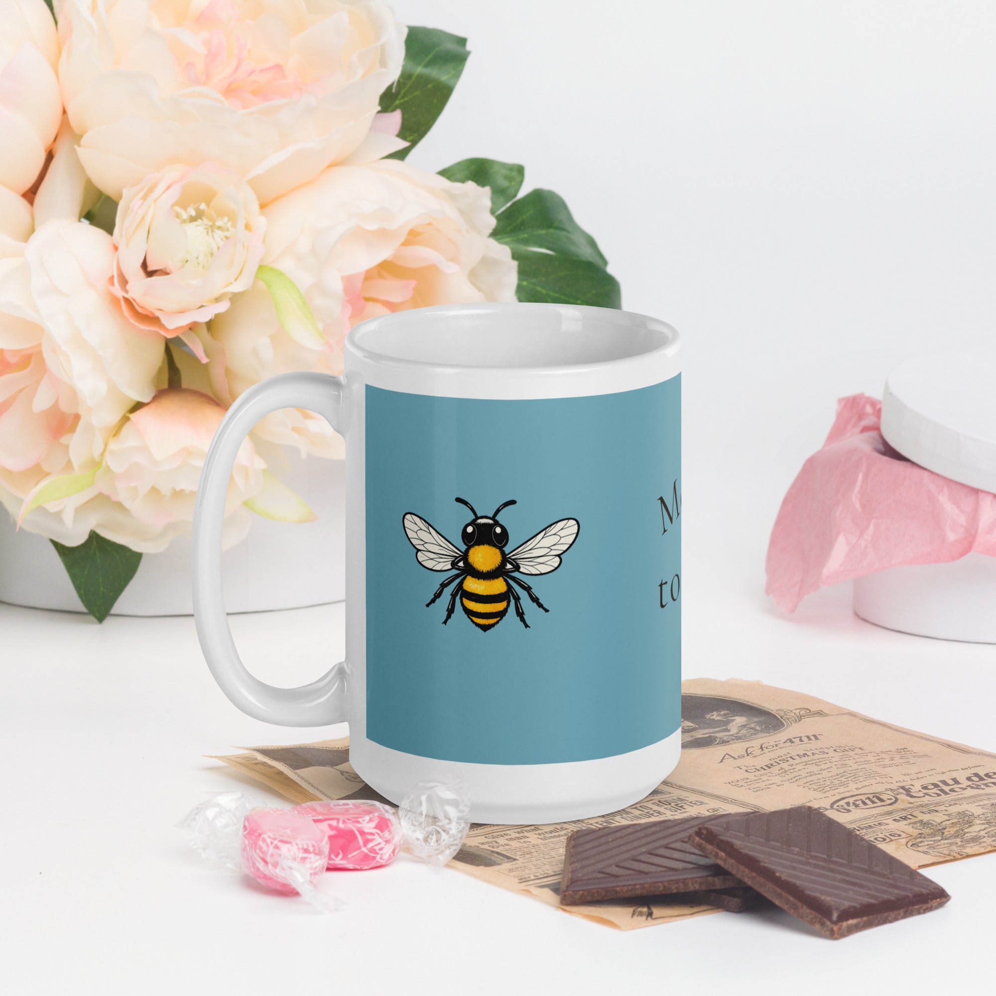 Blue ceramic coffee mug with bee illustration, front-left view, white rim and handle.