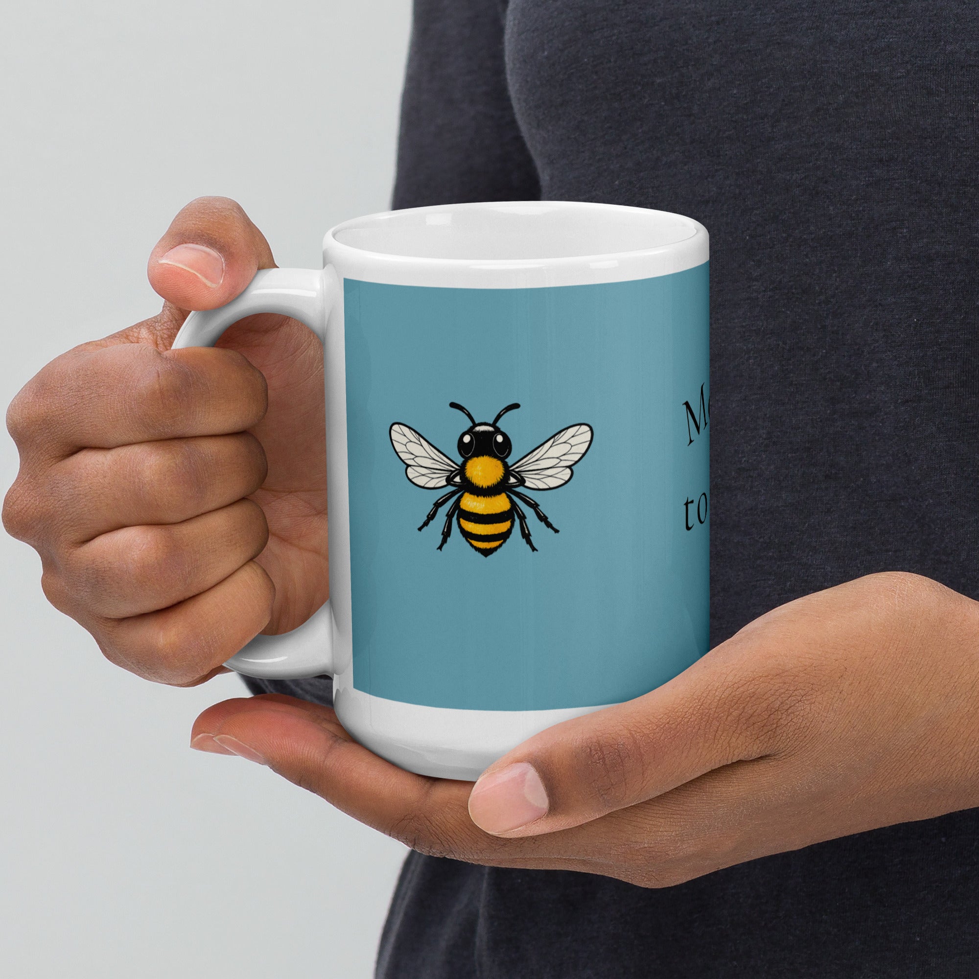 Close-up: blue ceramic coffee mug with bee illustration held by hands