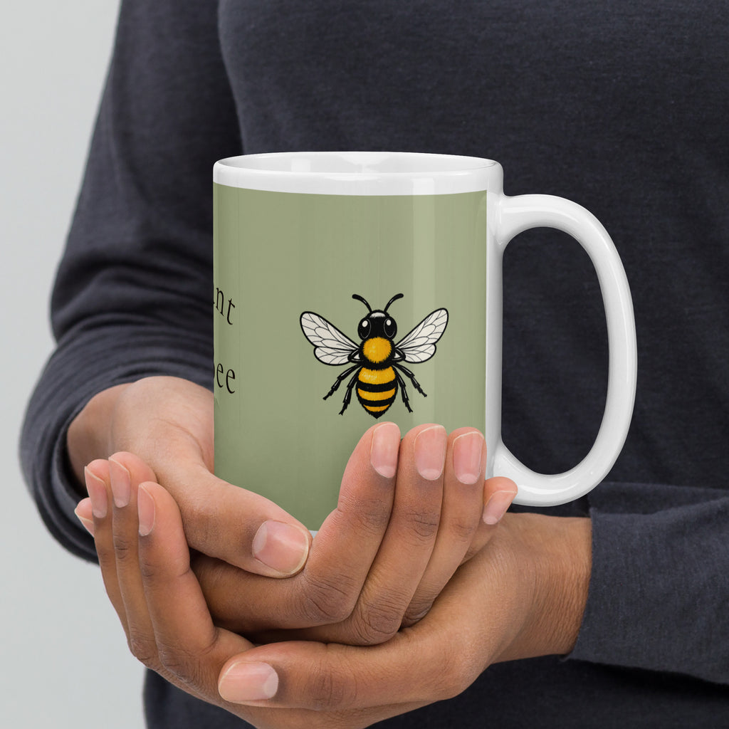 Sage green ceramic coffee mug with bee illustration, white handle, held by hands