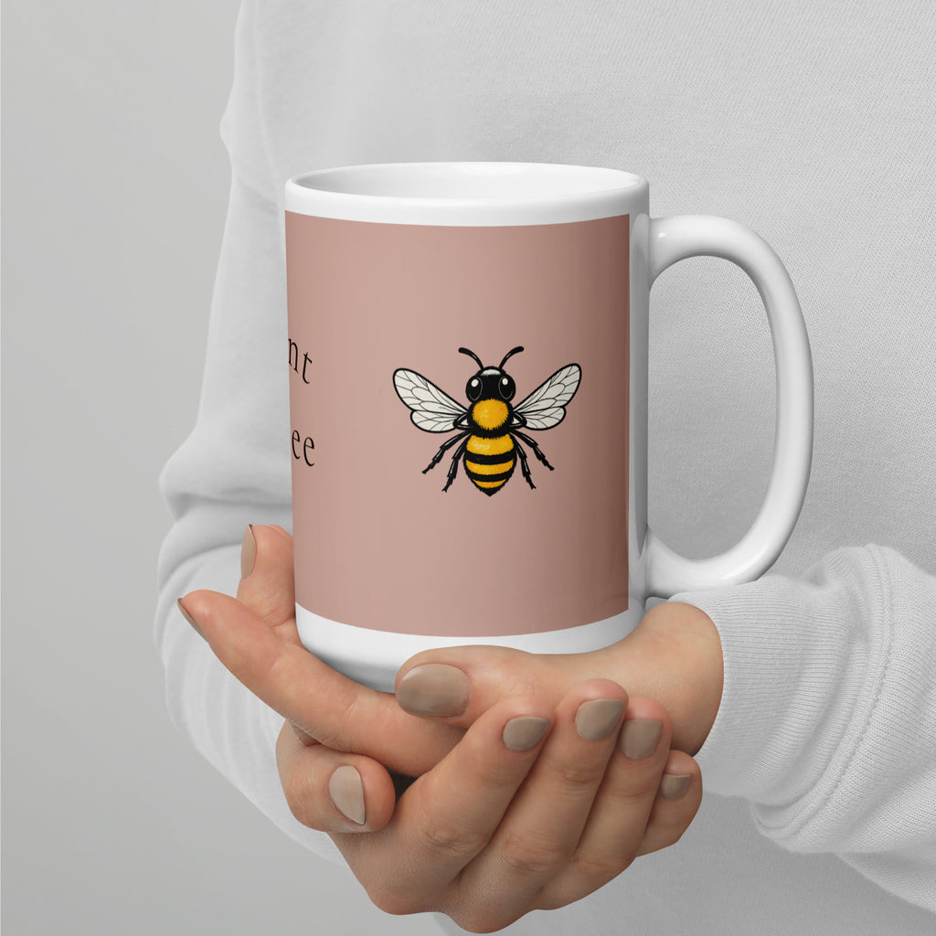 Dusty rose ceramic mug with bee illustration and white rim, held in hands