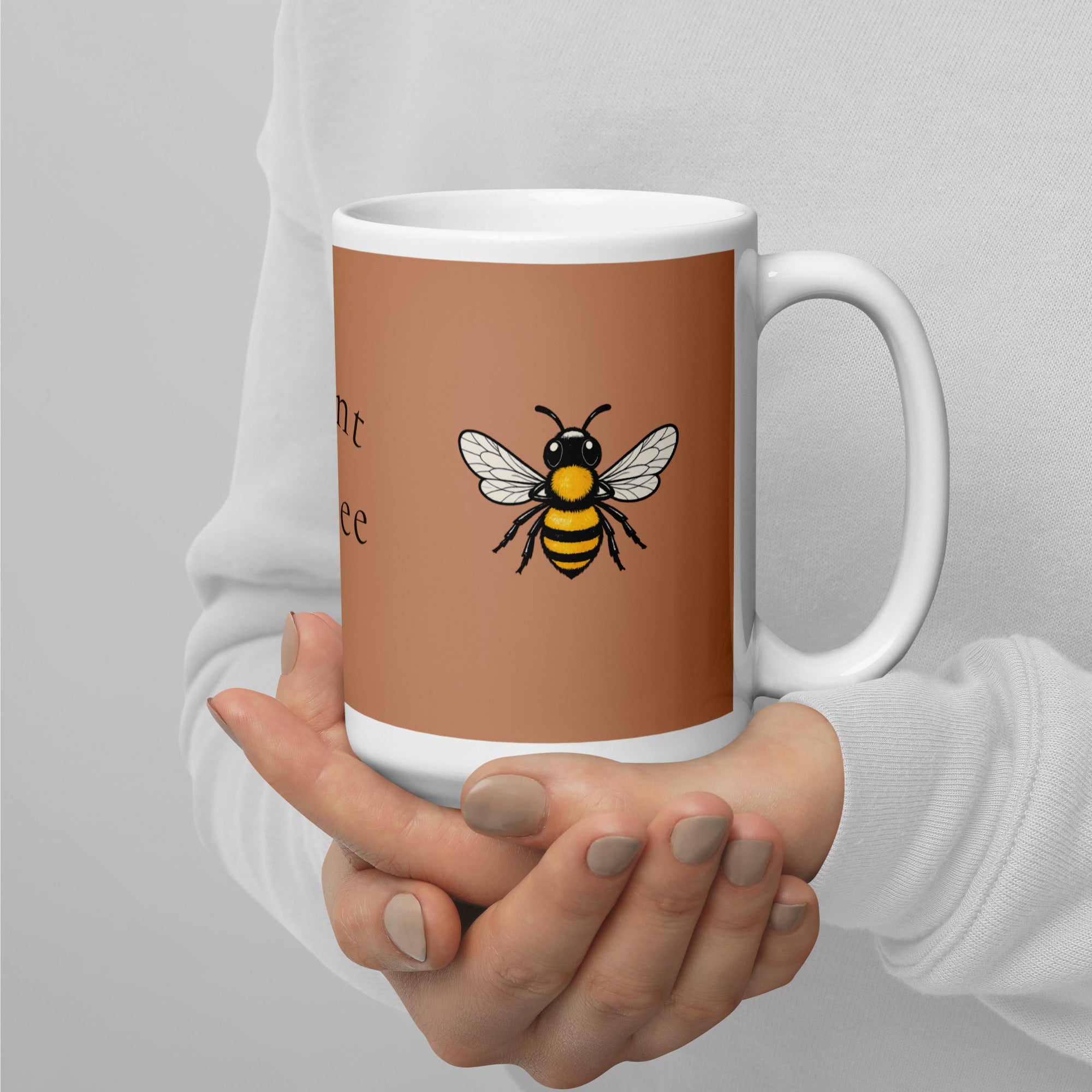 Brown ceramic mug with bee graphic, held close by two hands around the base and handle.
