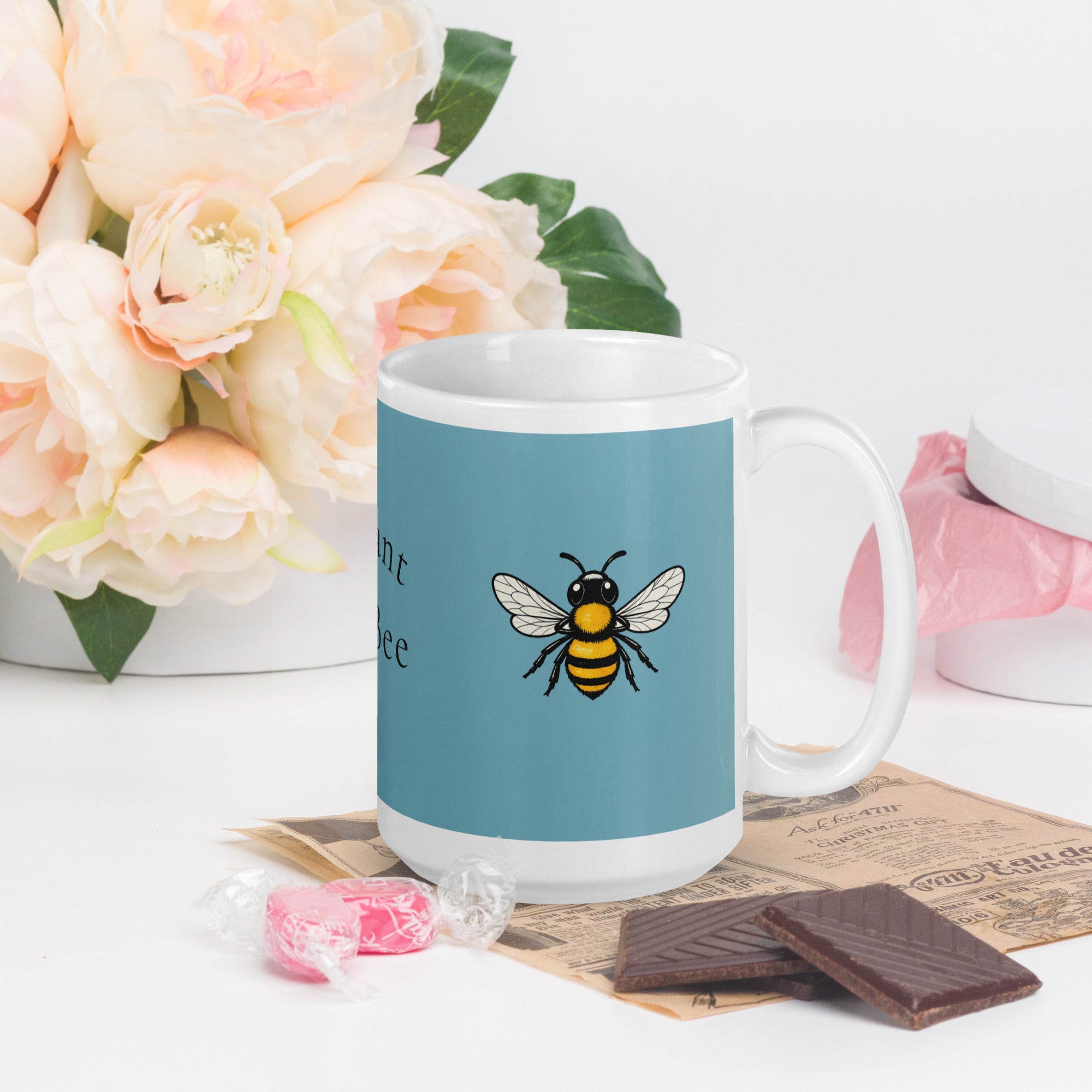 Blue ceramic coffee mug with bee illustration on front, white handle and rim.