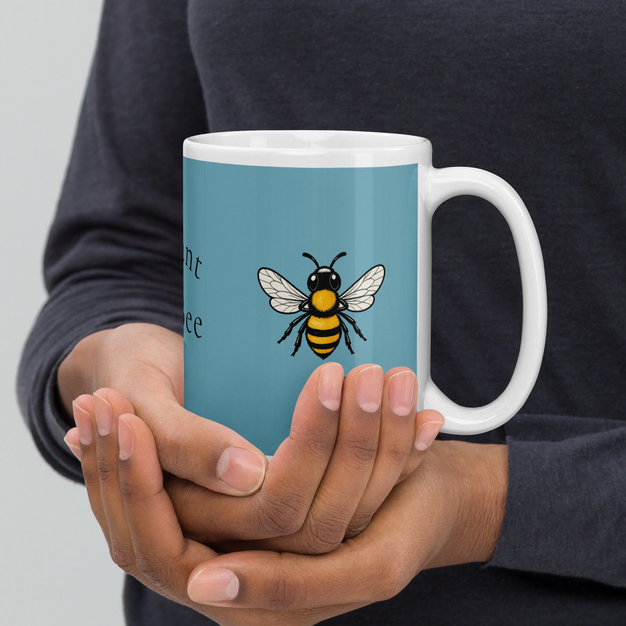 Blue ceramic mug with white rim and handle, bee illustration held in hands
