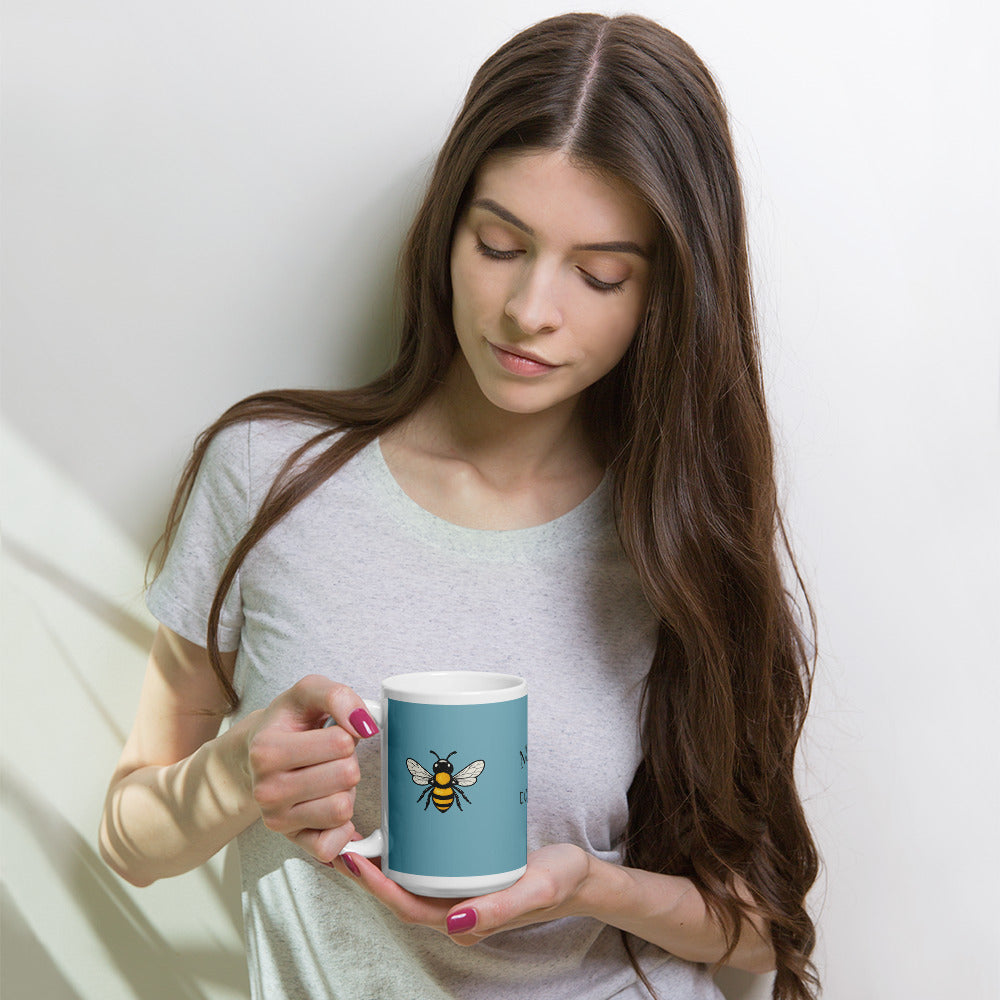 Blue ceramic coffee mug with bee illustration held in both hands