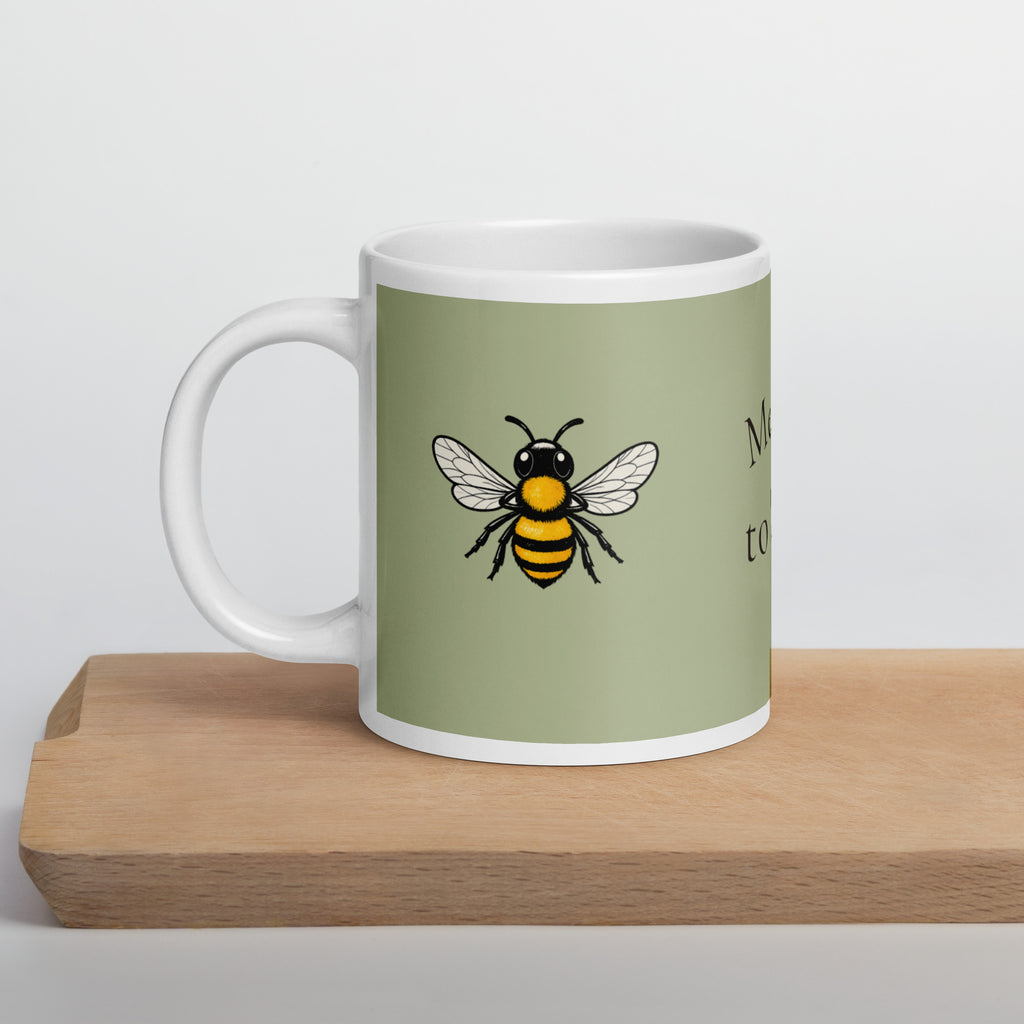 Sage green ceramic mug with white handle and black-and-yellow bee illustration
