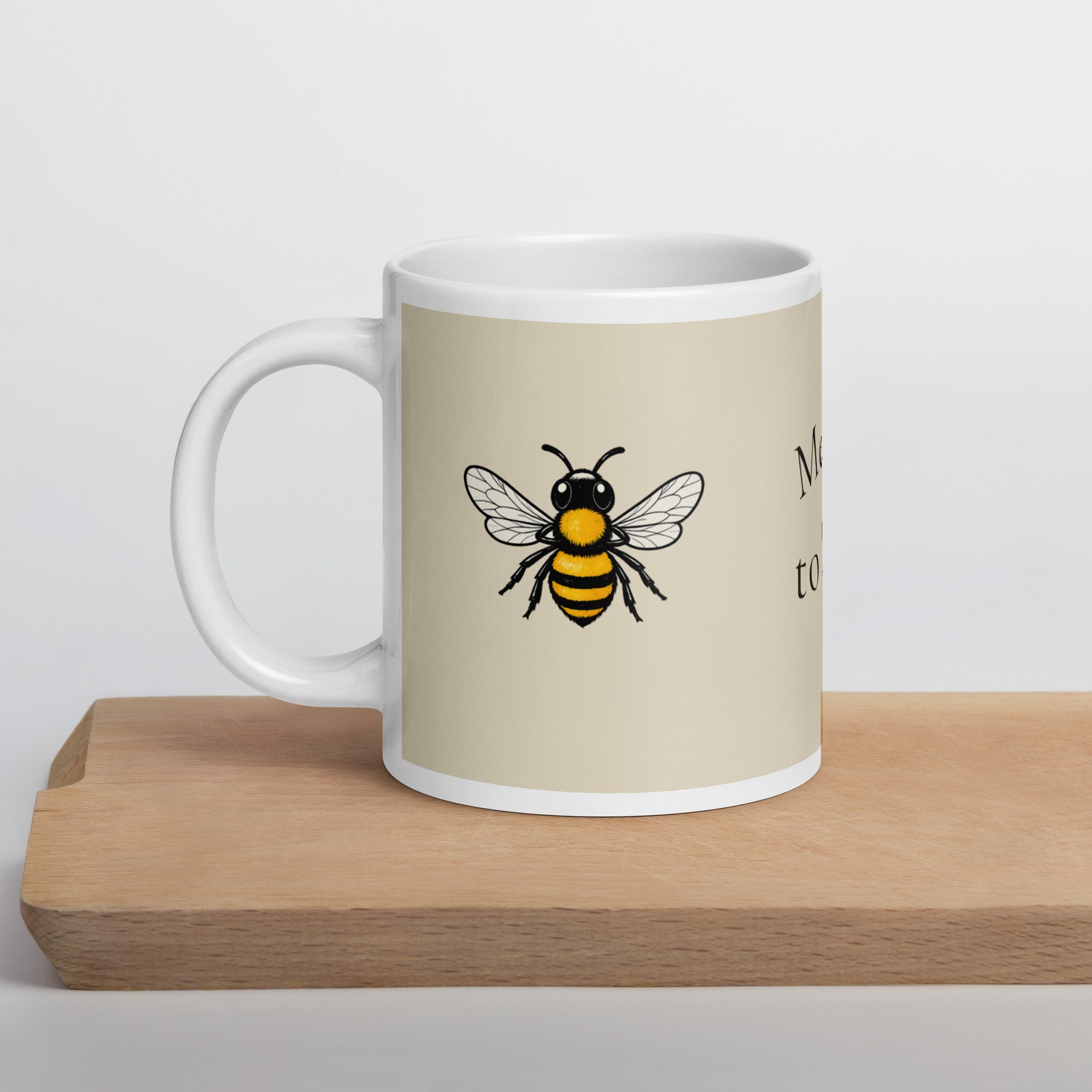 Light beige ceramic coffee mug with bee illustration on side, front view
