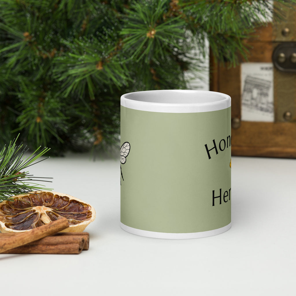 Sage green ceramic mug with partial “Honey” and “Herbs” text, white rim
