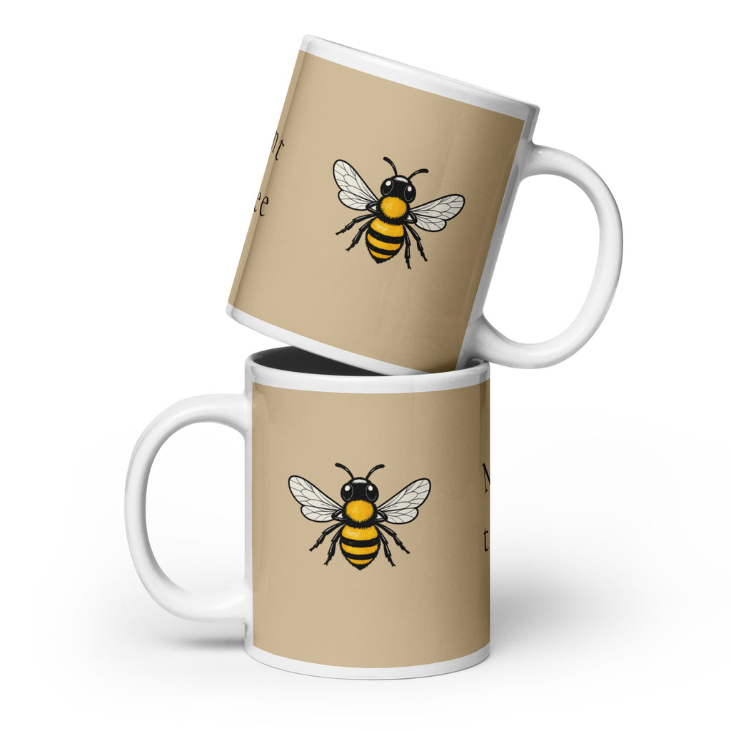 Beige ceramic coffee mug with bee illustration and white handle, angled view