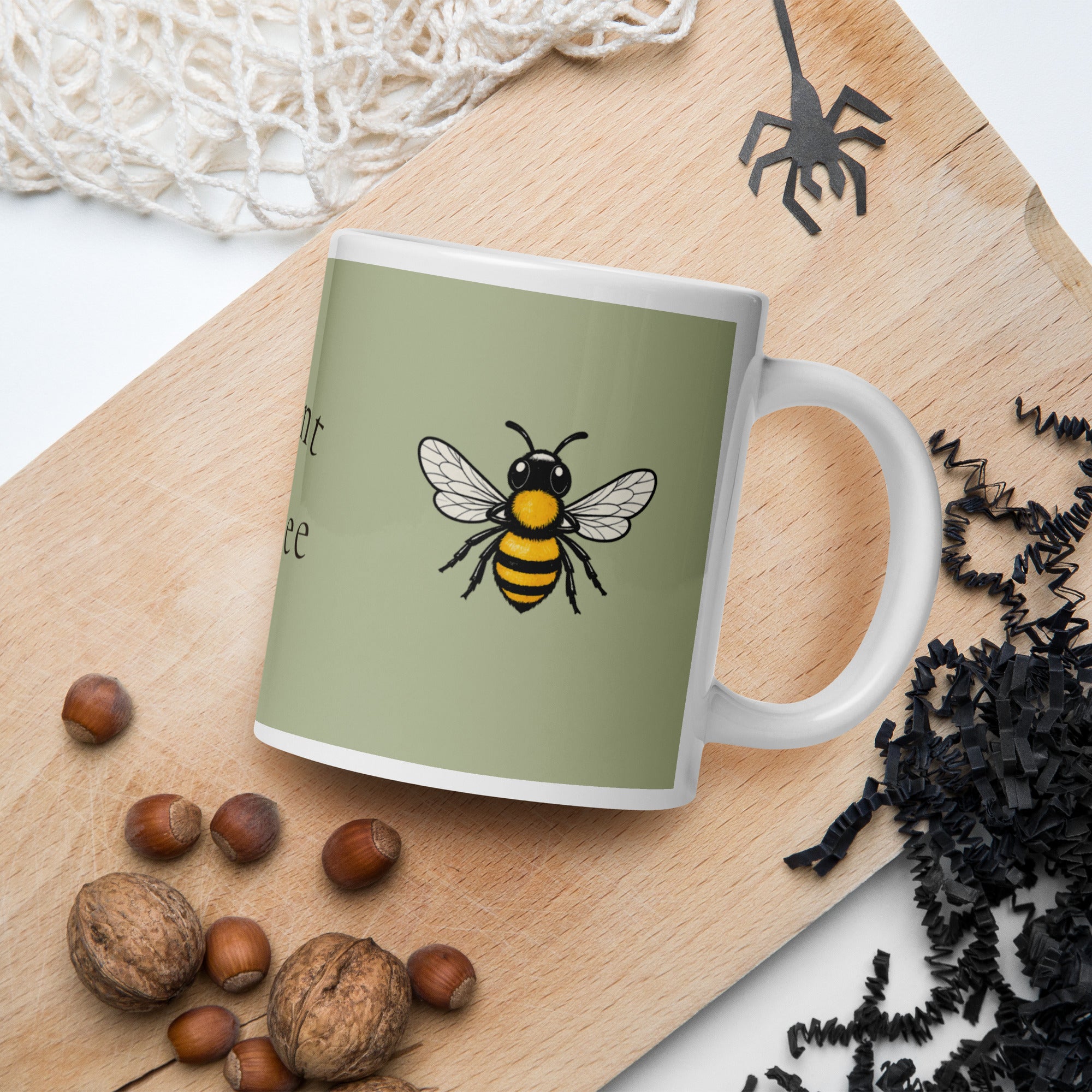 Sage green ceramic coffee mug with white handle and centered bee illustration on front