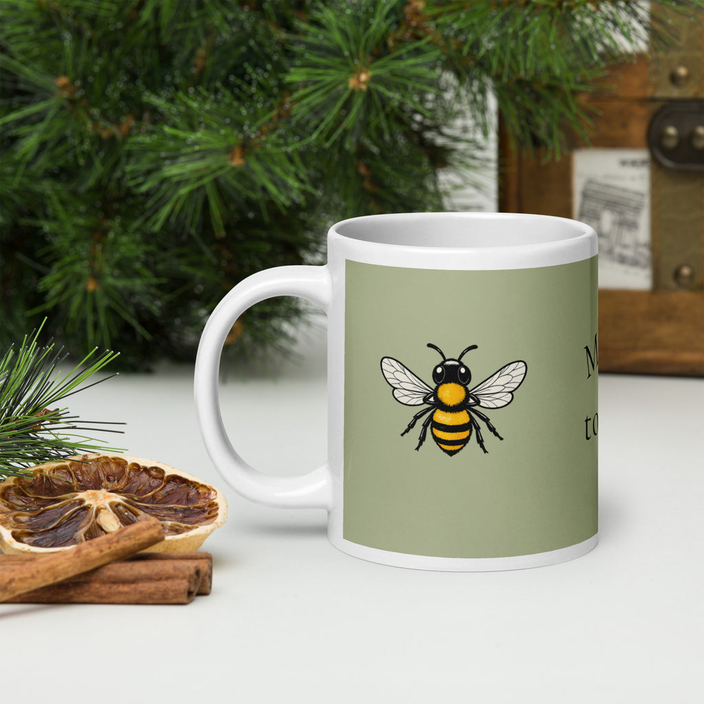 Sage green ceramic mug with white handle and bee illustration on front