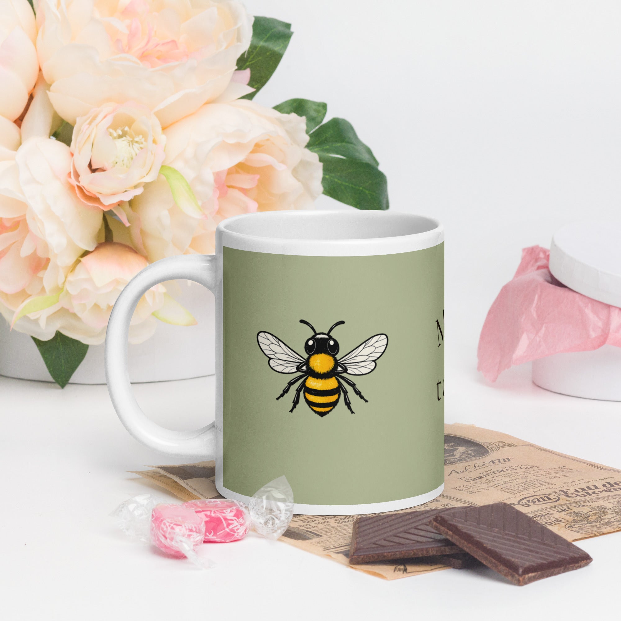 Sage green ceramic mug with white handle and large bee illustration