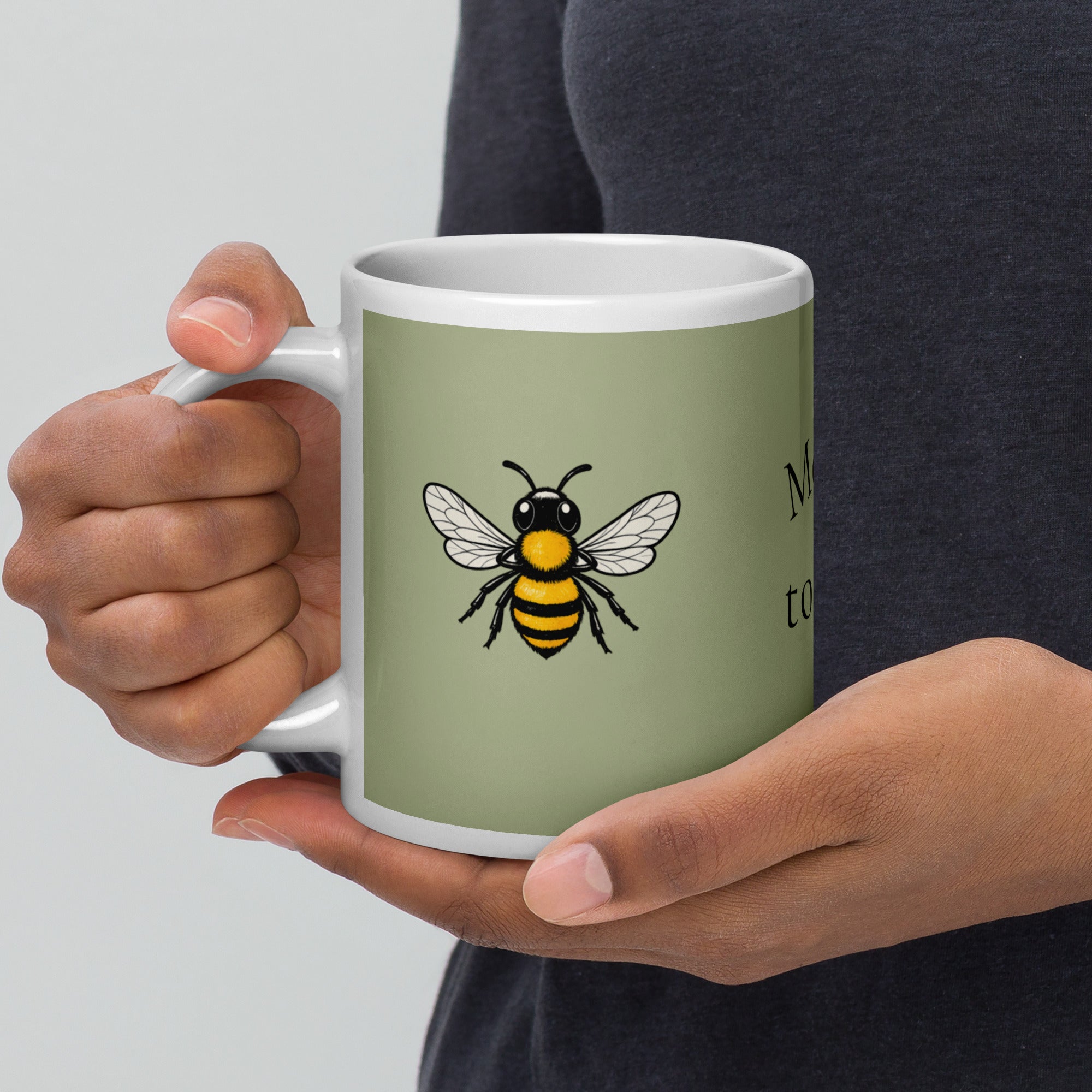 Sage green ceramic coffee mug with white handle and black-yellow bee illustration