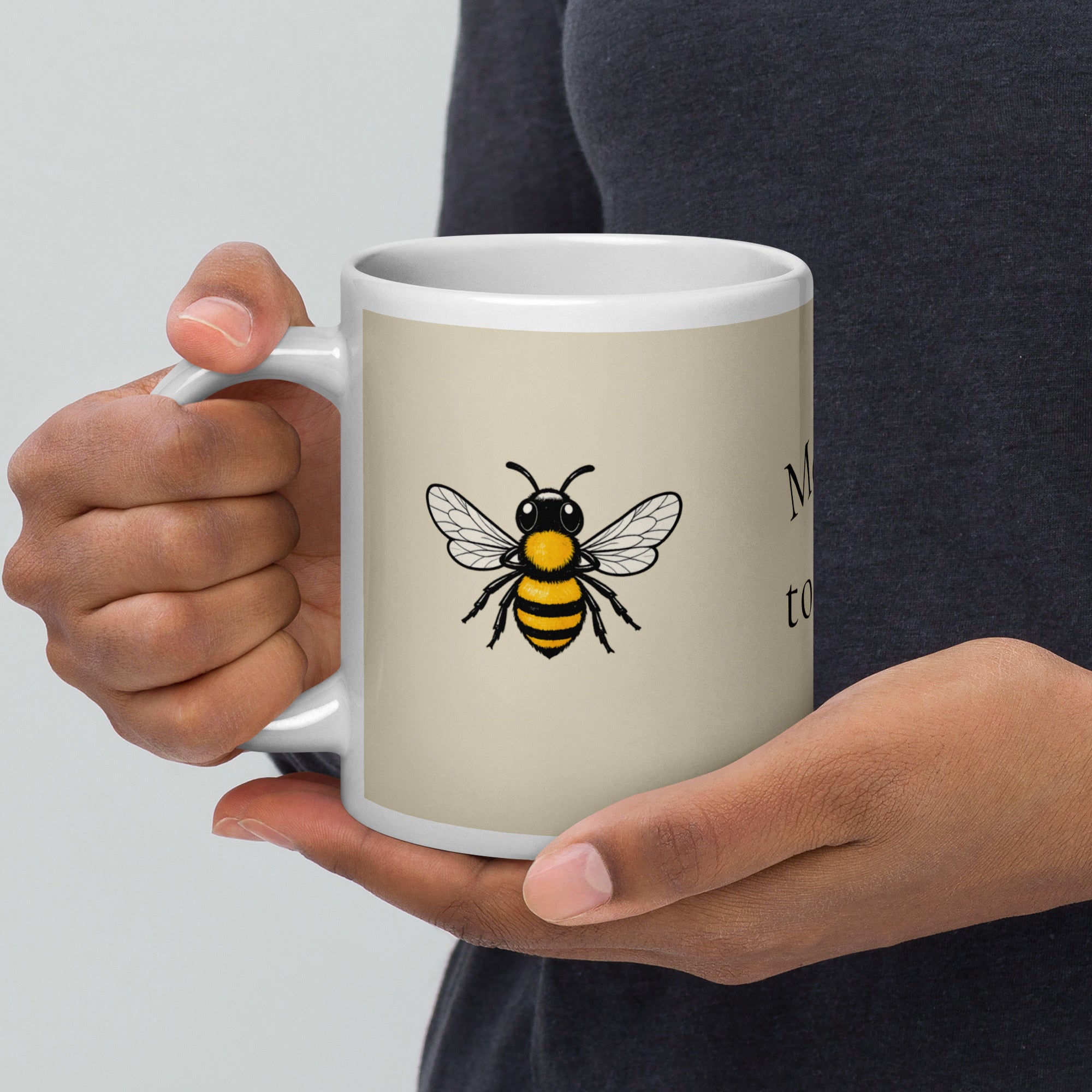 Light beige ceramic coffee mug with white handle and bee illustration on front