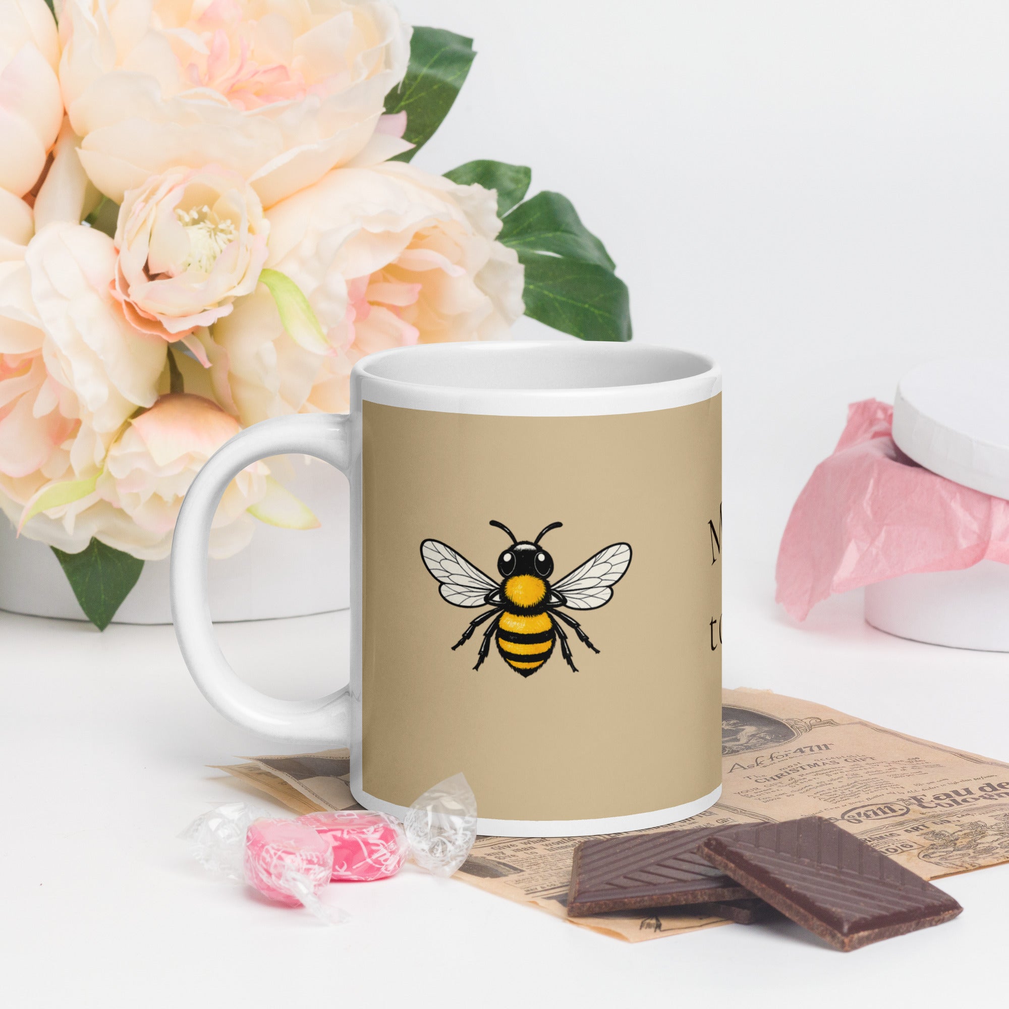 Beige ceramic coffee mug with bee illustration and white handle, angled view